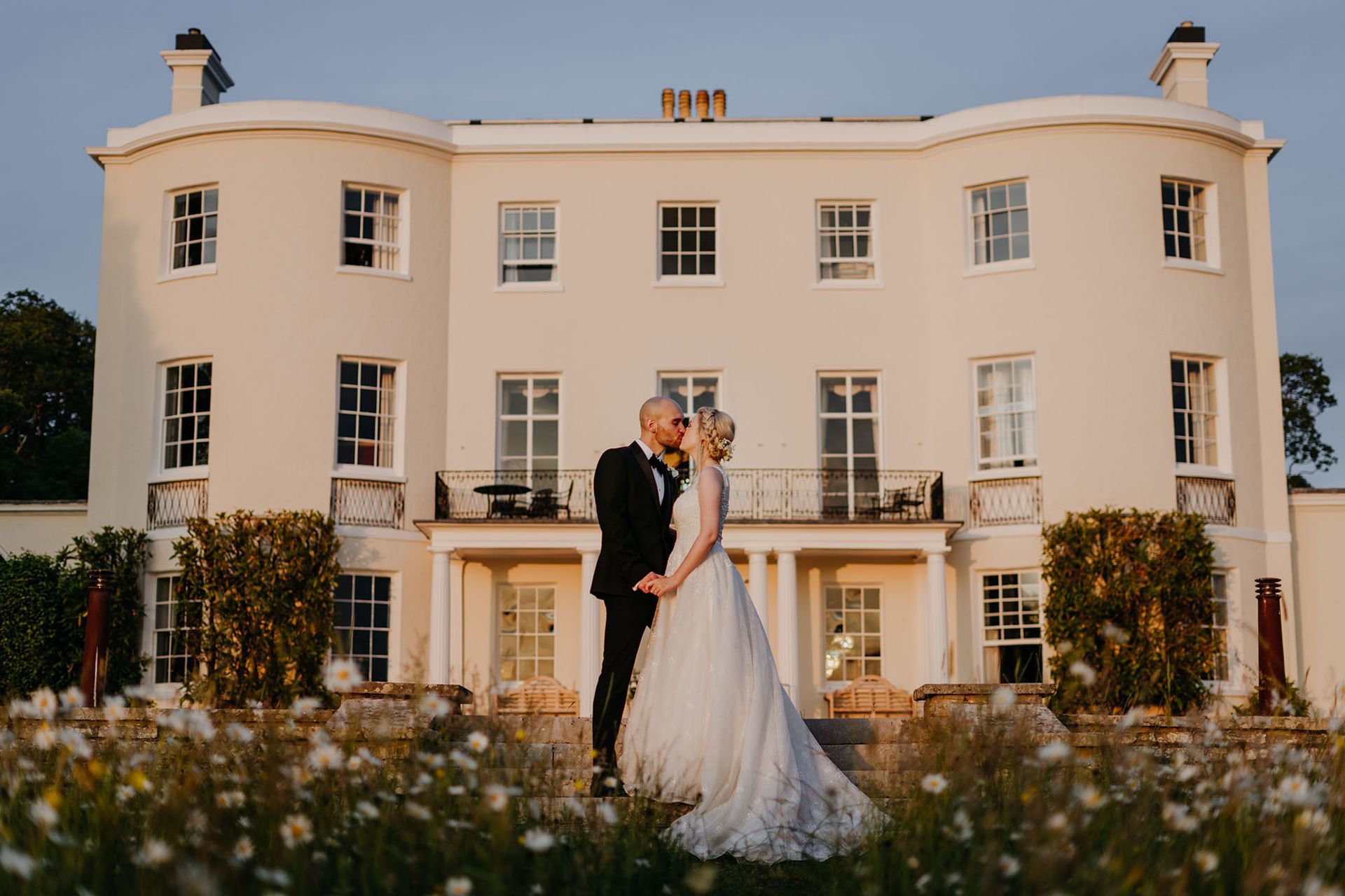 a bride and groom are kissing in front of a large white building .