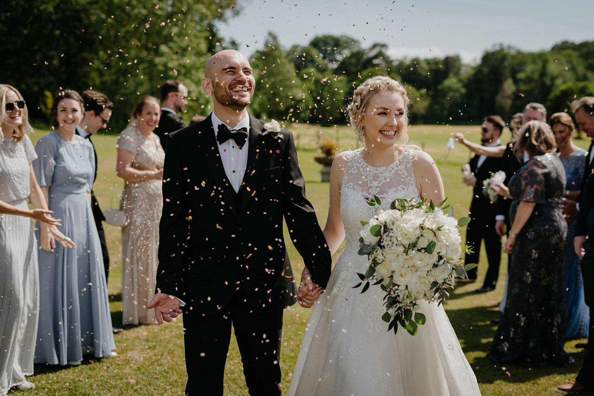 a bride and groom are walking through a field of confetti .