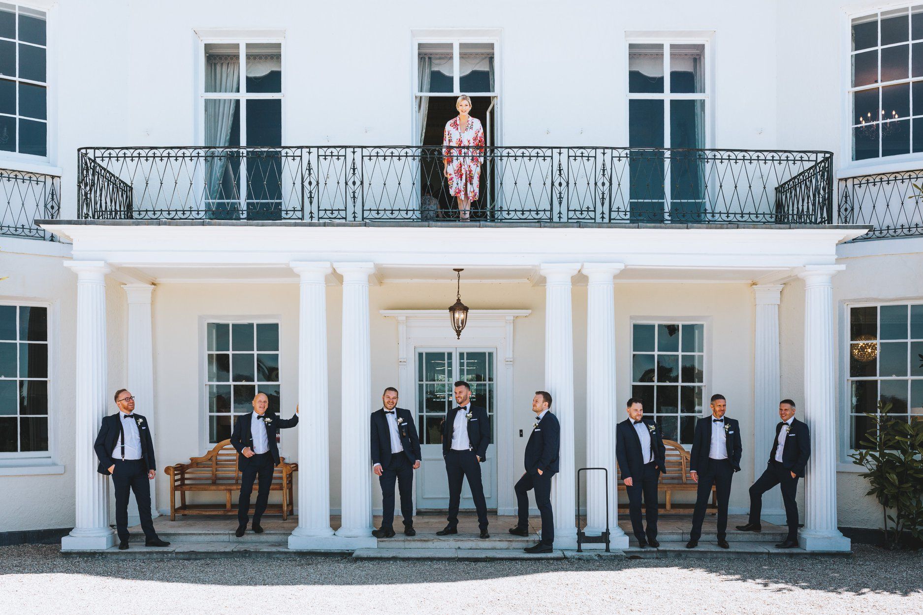 a bride and her groomsmen are posing for a picture in front of a large white building .