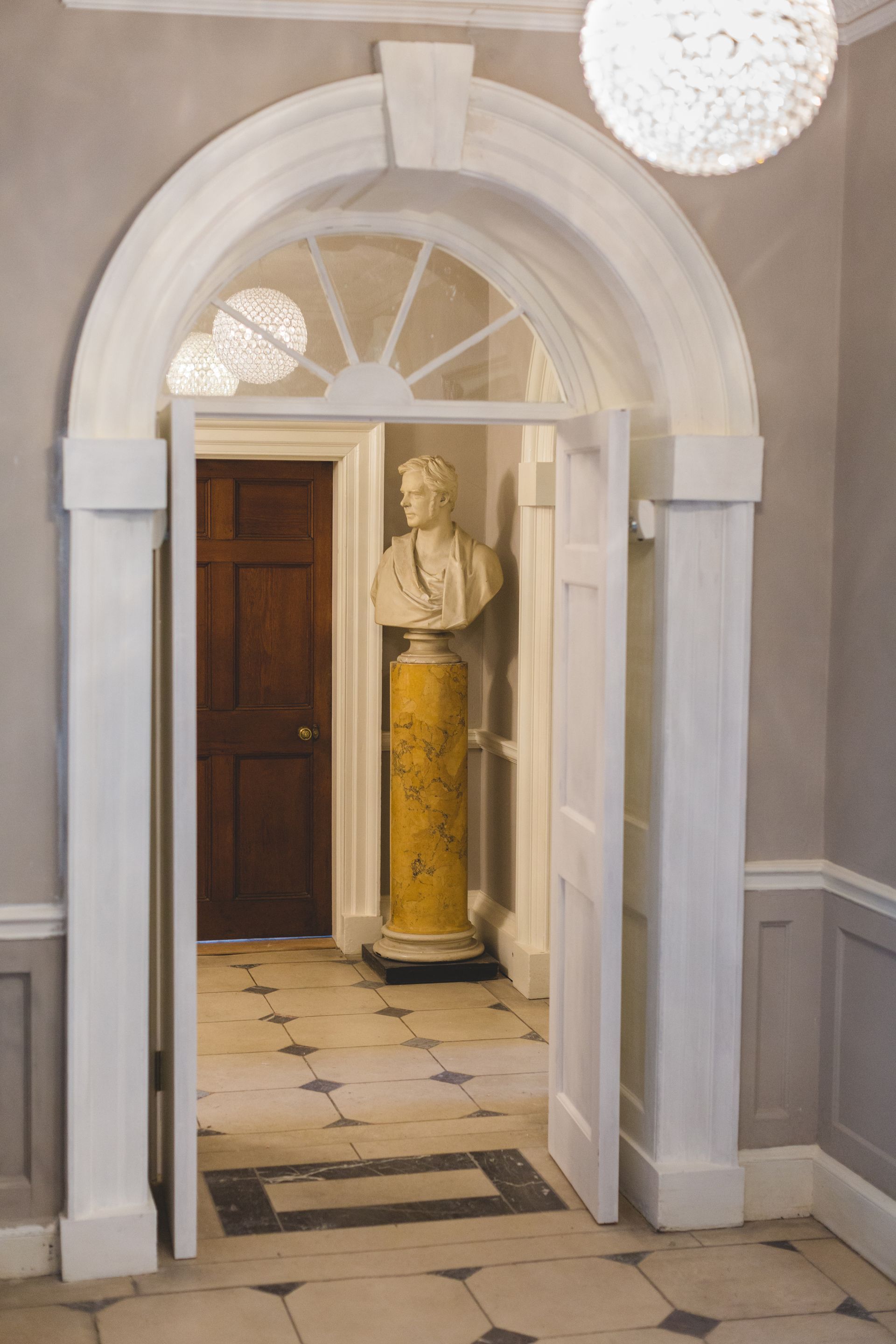 a statue of a man is sitting on a pedestal in a hallway .