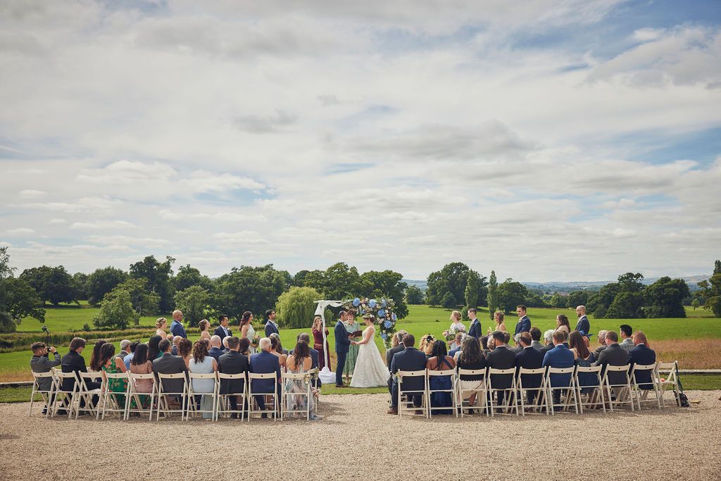 a group of people are sitting in chairs watching a wedding ceremony .