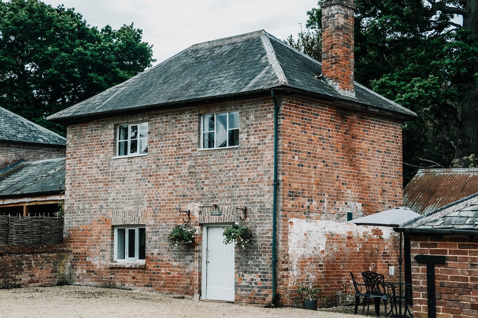 A large brick house with a chimney and a white door. Cottage on wedding venue.