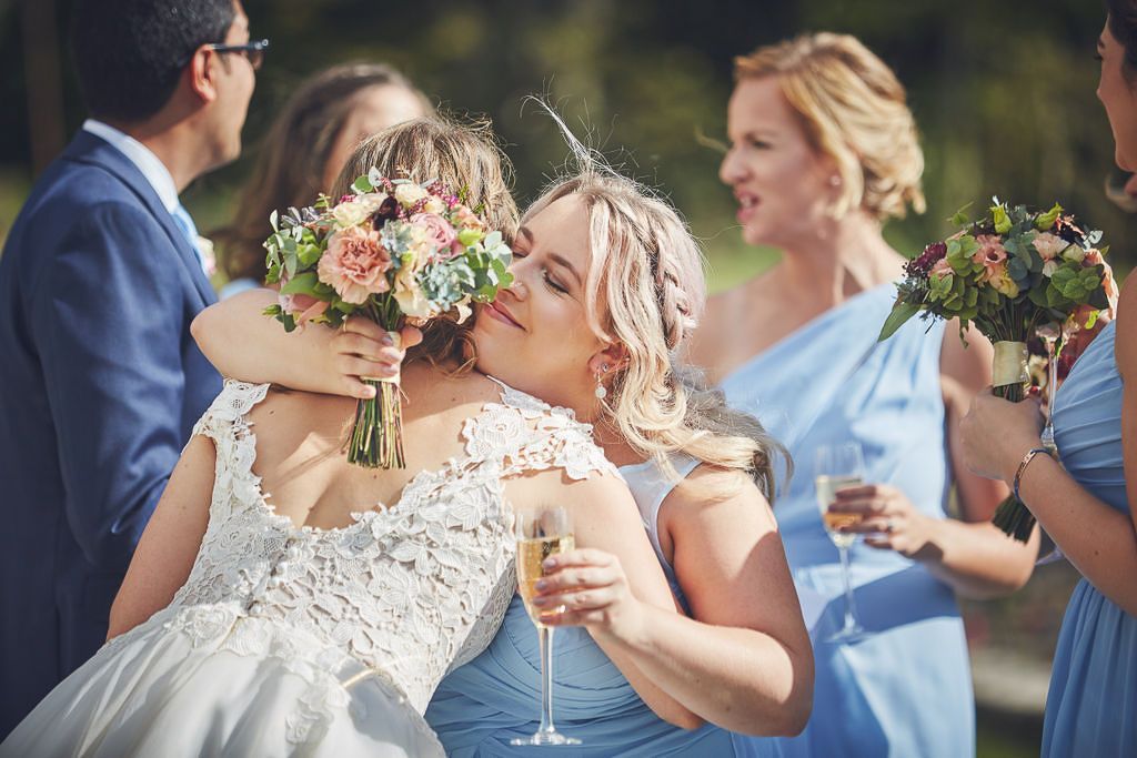 a bride and her bridesmaids are hugging each other at a wedding .