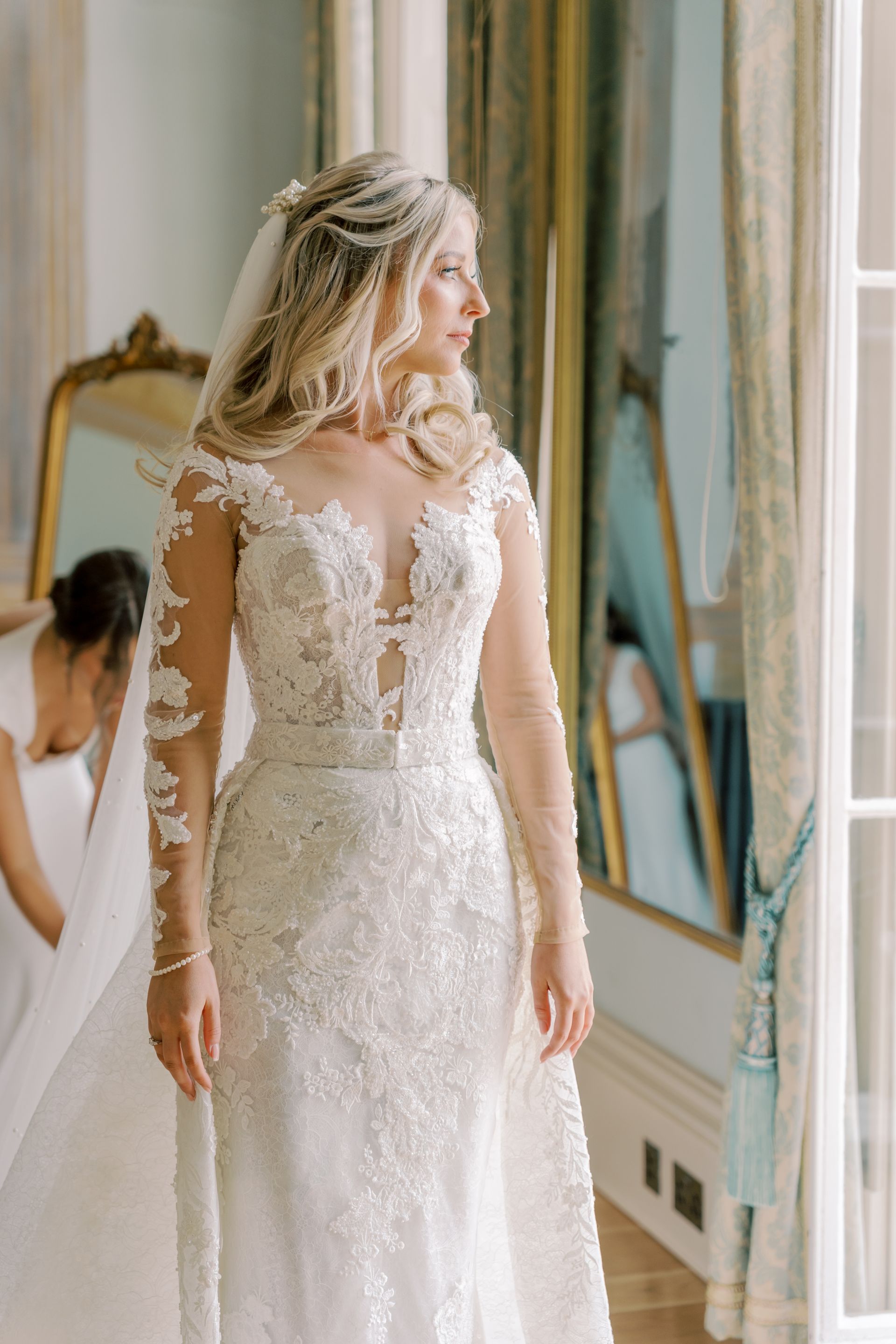 a bride in a wedding dress is standing in front of a mirror.