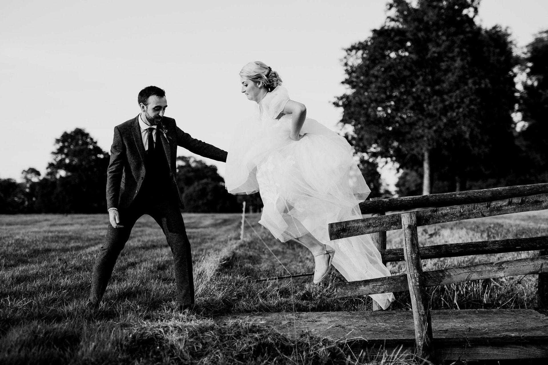 a black and white photo of a bride and groom holding hands
