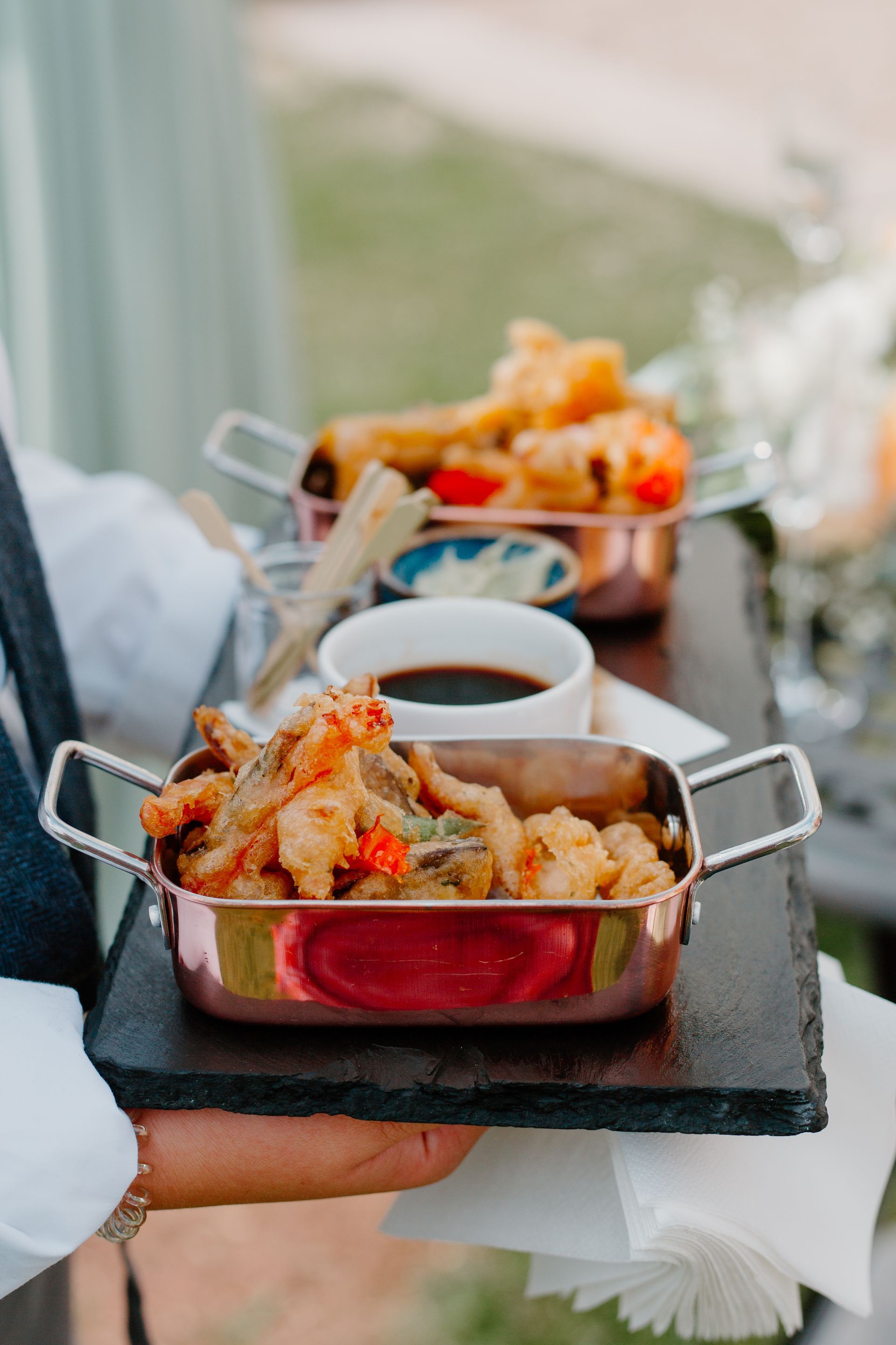 a person is holding a tray of food on a table .