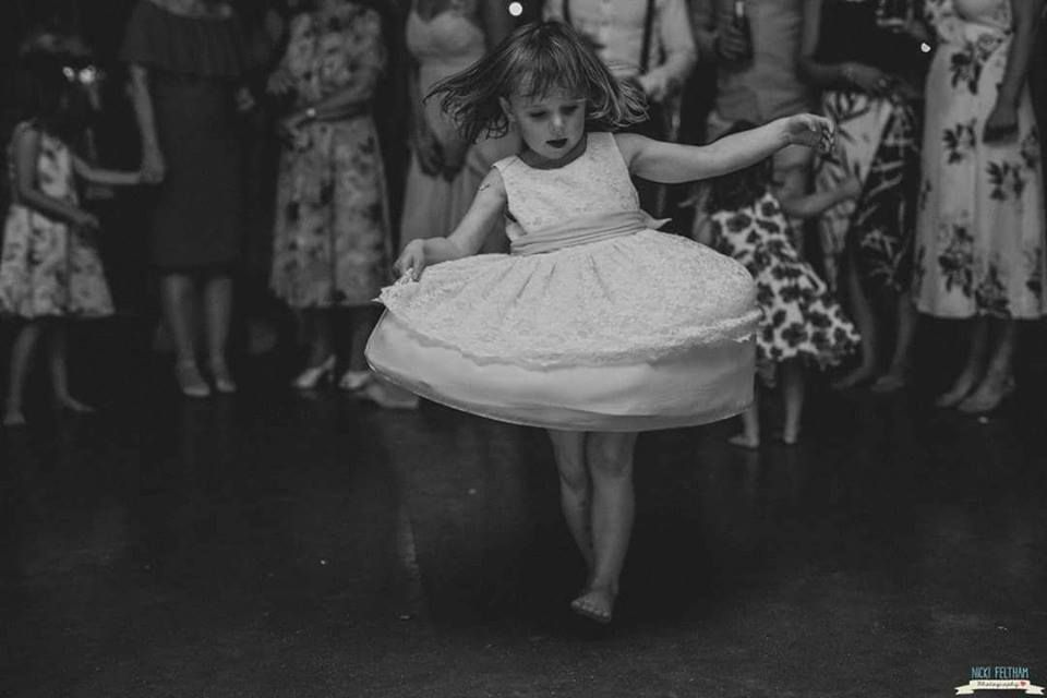 a little girl in a white dress is dancing on a dance floor .