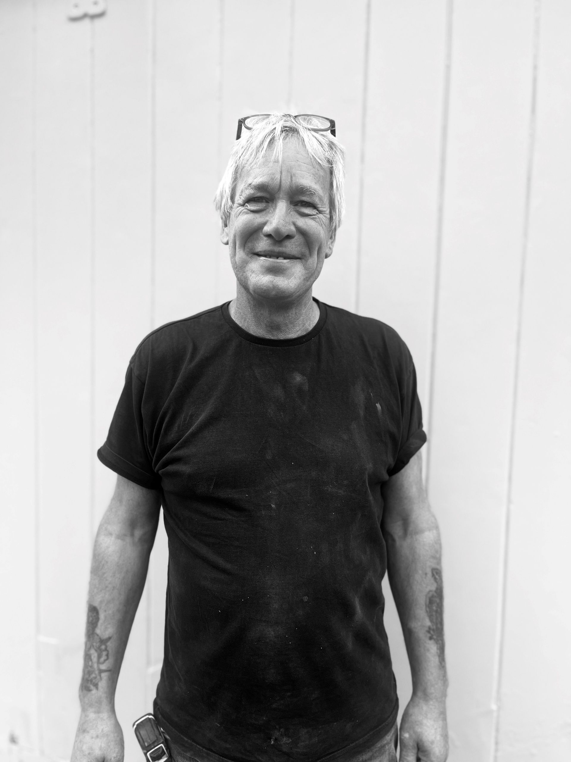 a man in a black shirt is standing in front of a white wall .
