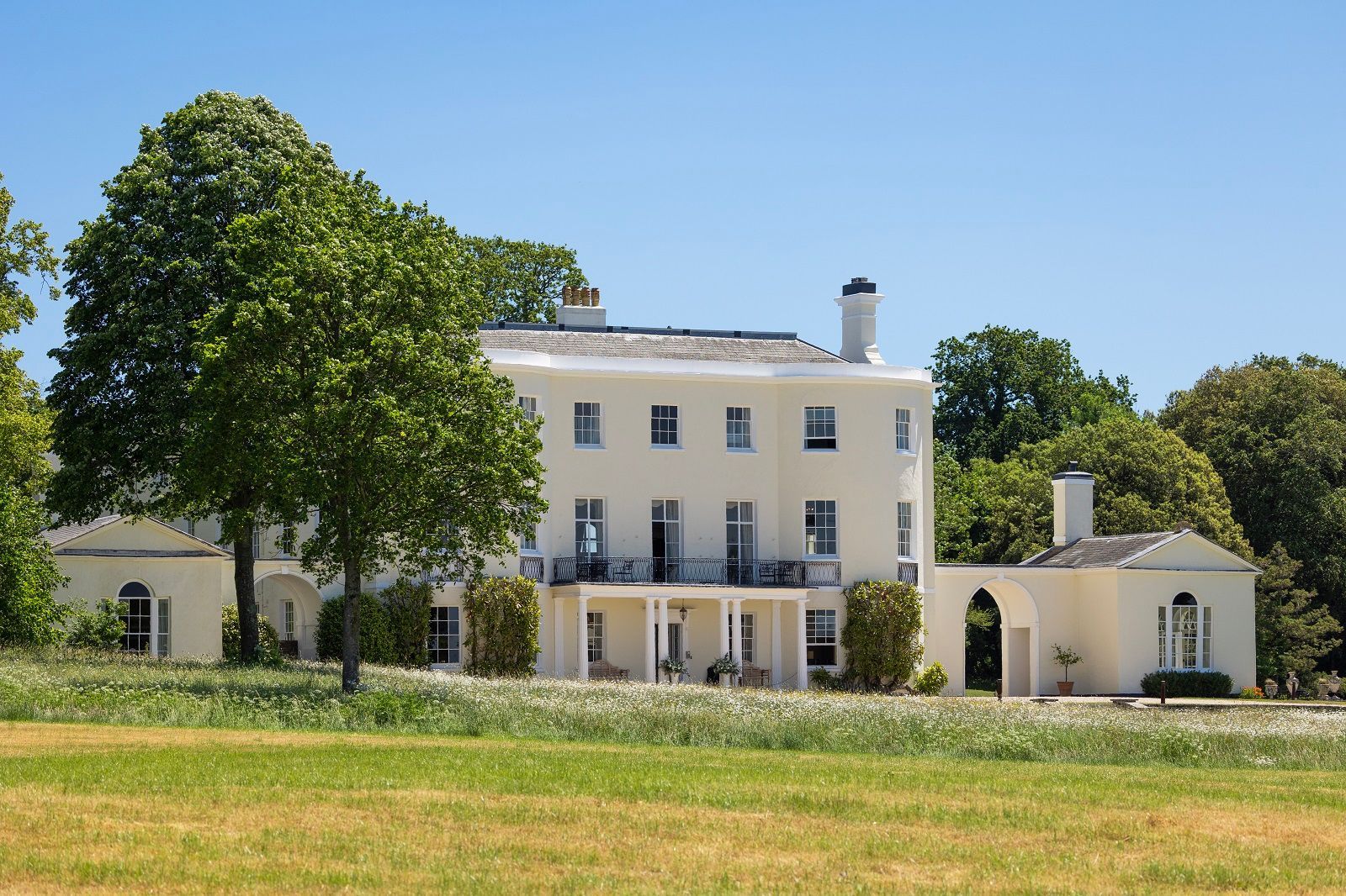 a large white house sits in the middle of a grassy field