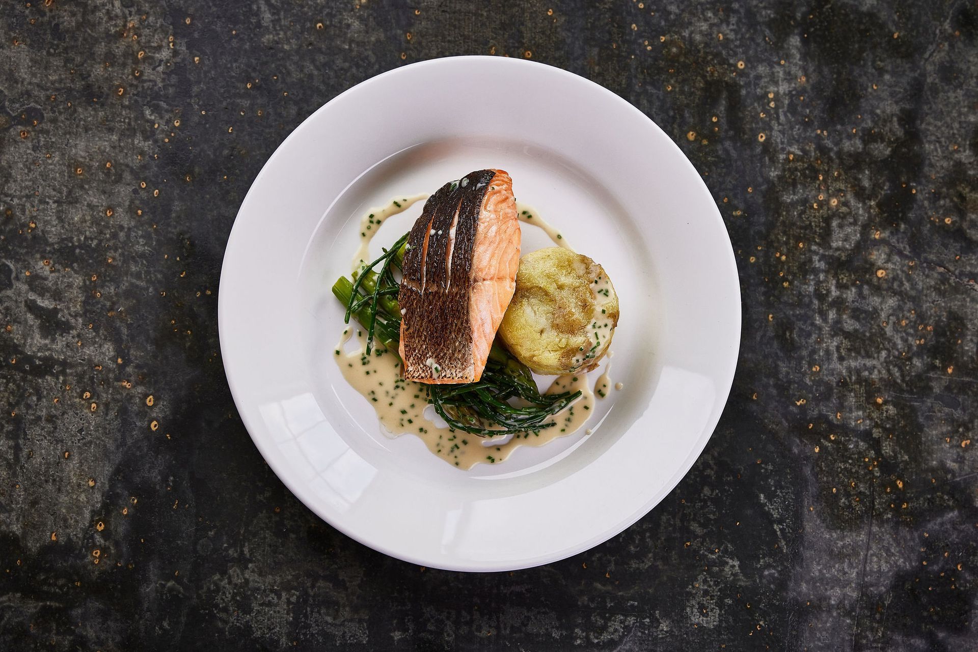 a white plate topped with a piece of salmon and potatoes .