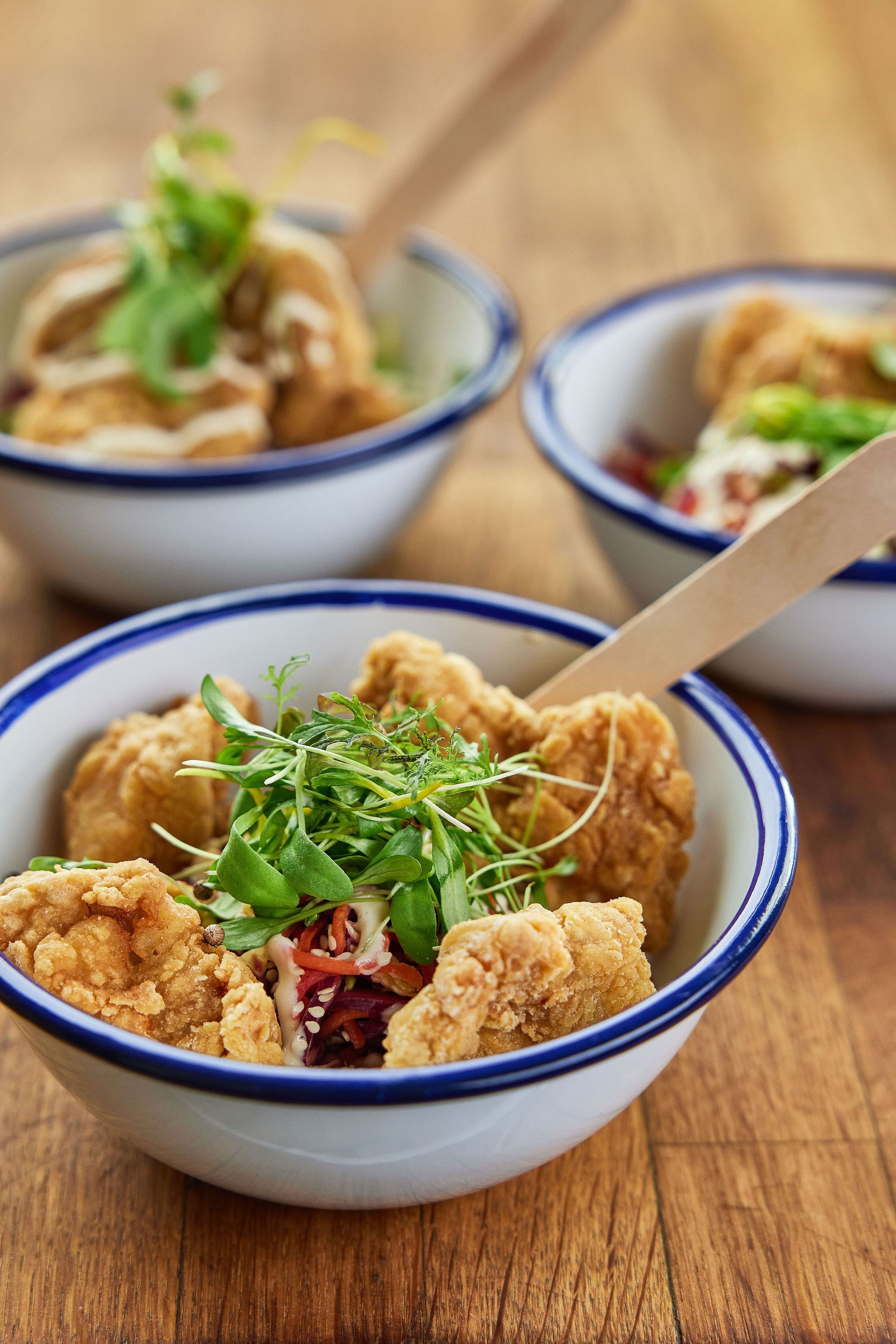a bowl of food with a wooden spoon in it on a wooden table .