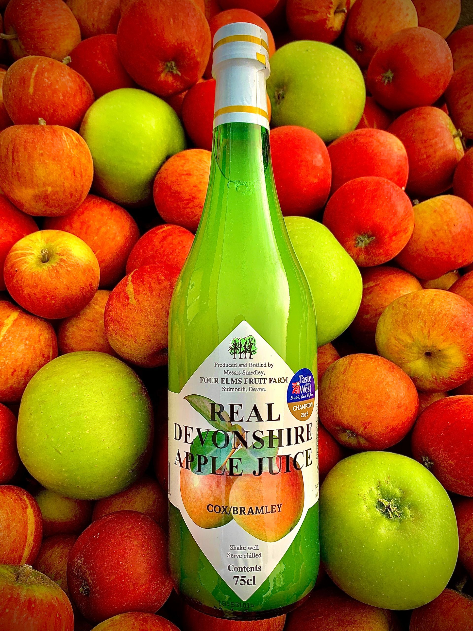 a bottle of real bentonshire apple juice surrounded by apples