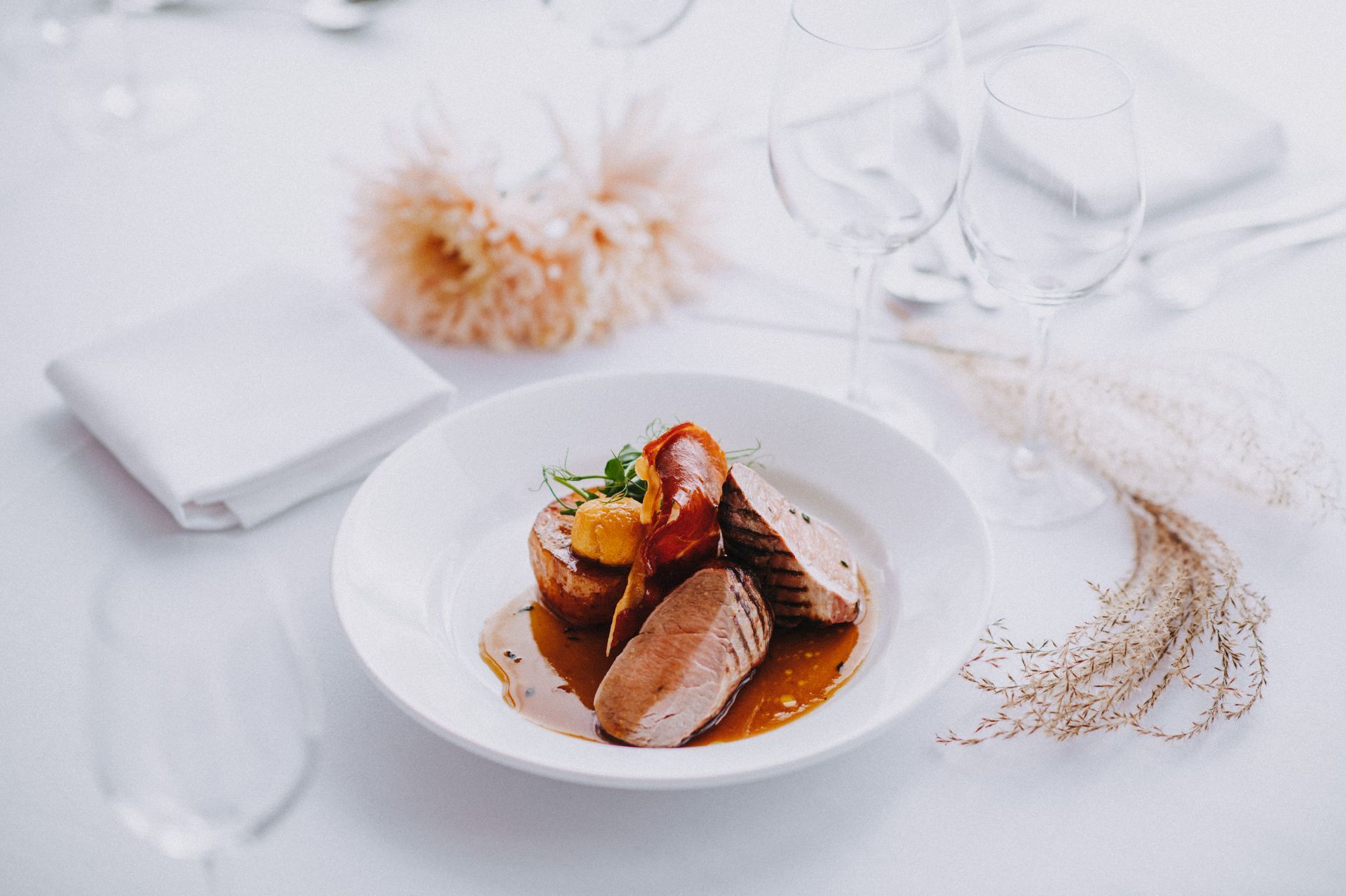 a white plate topped with meat and sauce on a table .
