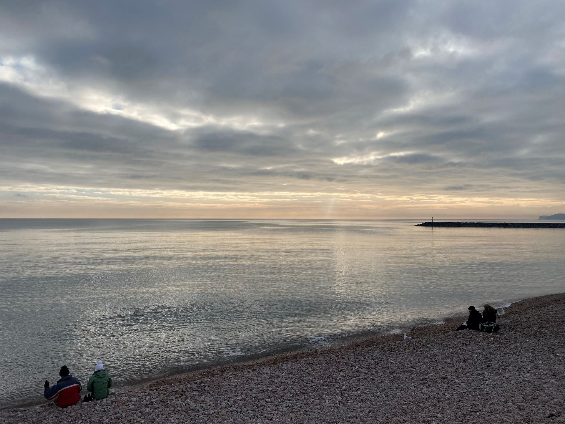 a group of people are sitting on a beach near the ocean.