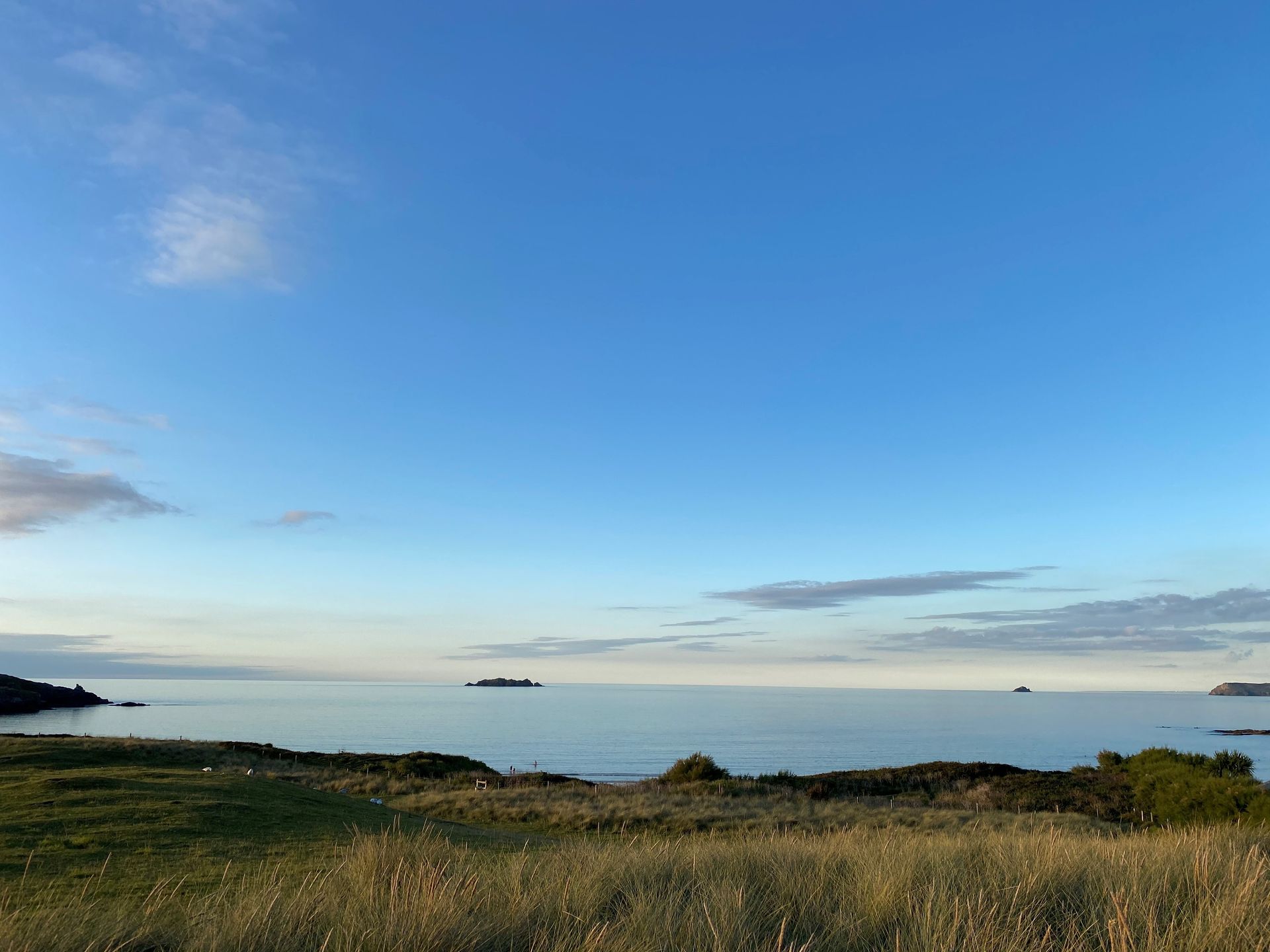 a large body of water is surrounded by a grassy field on a sunny day.