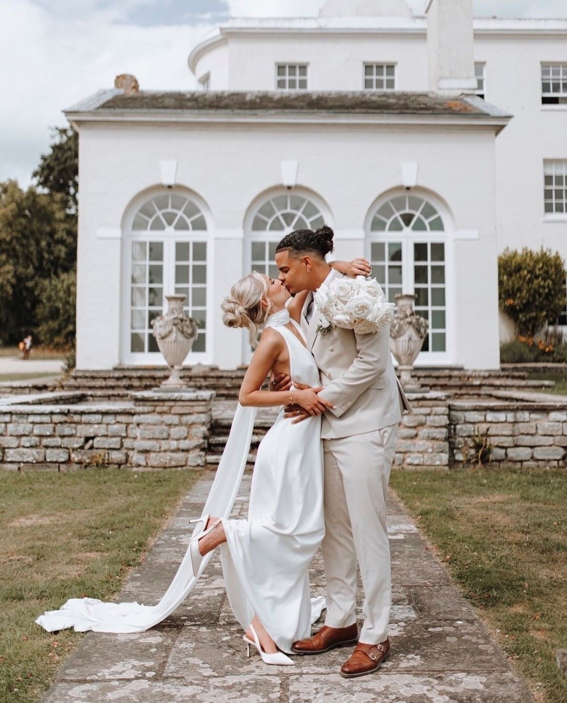 a bride and groom are posing for a picture in front of a large white building .