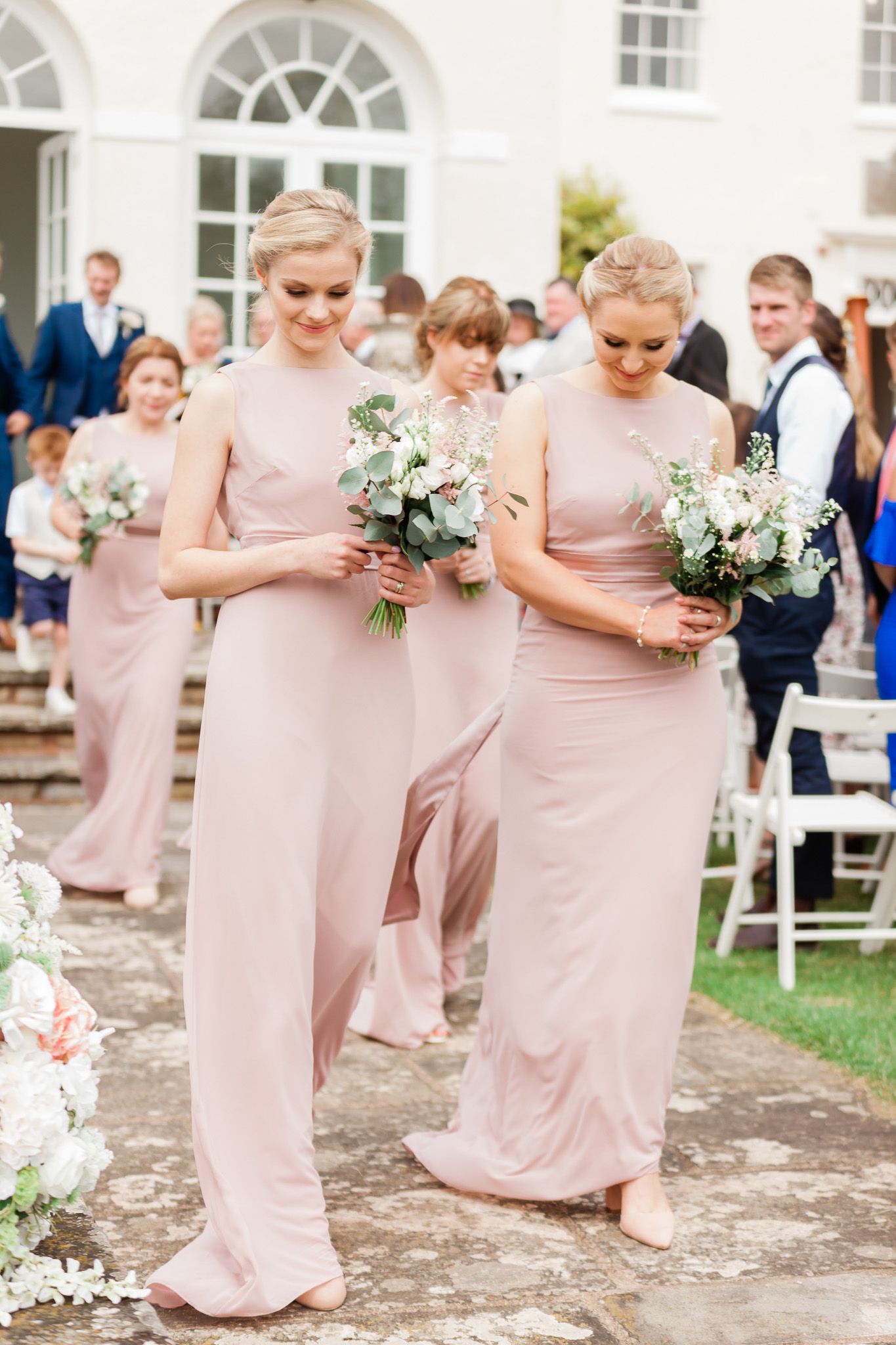 a group of bridesmaids are walking down the aisle at a wedding.