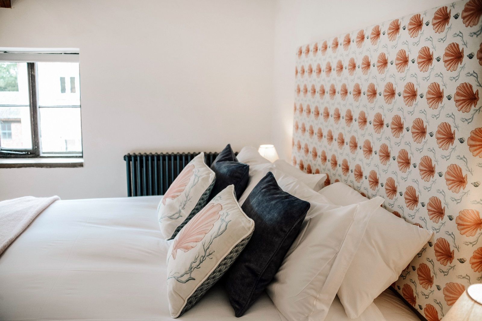 a bedroom with a bed , pillows , and a window .