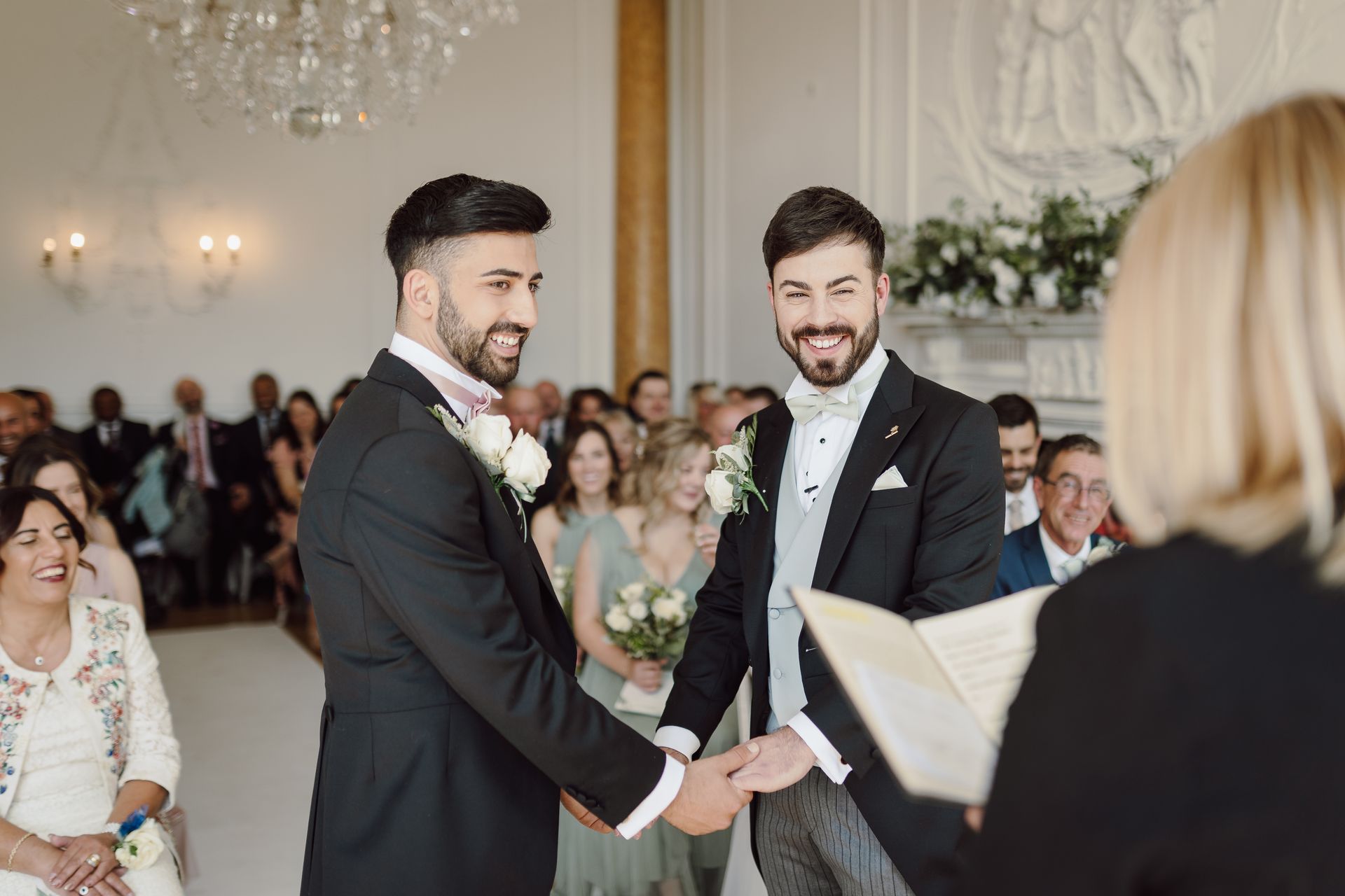two men are holding hands during a wedding ceremony .
