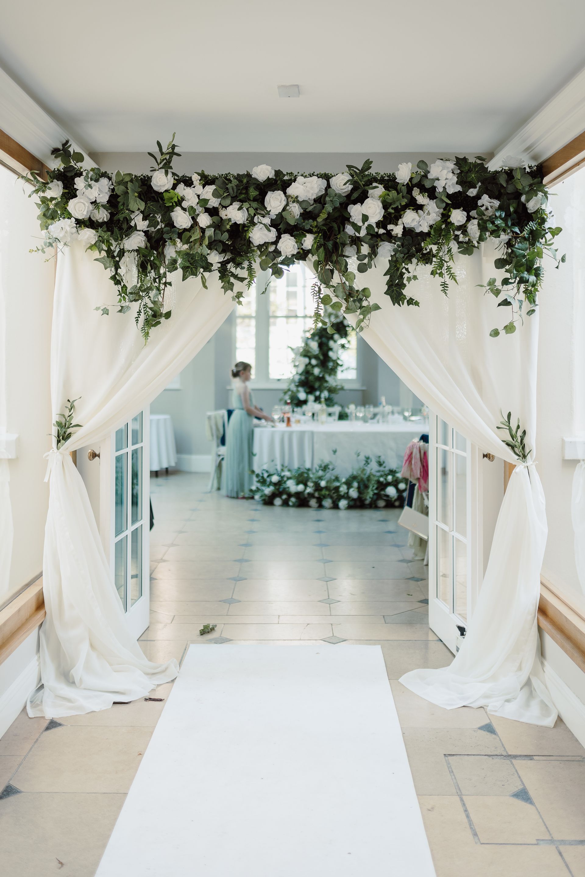 a hallway with a white carpet and flowers hanging from the ceiling .
