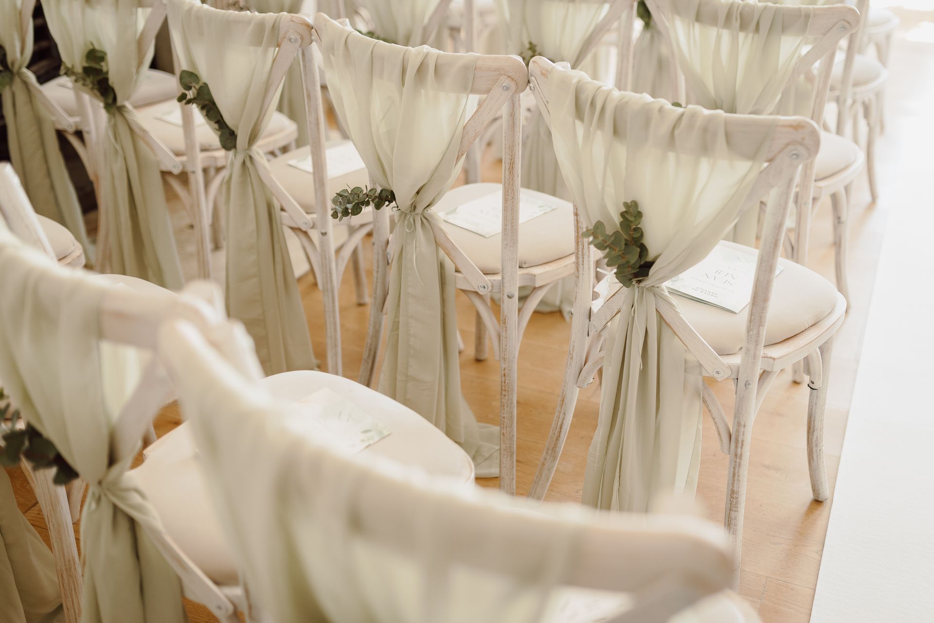 a row of white chairs are lined up in a row for a wedding ceremony .