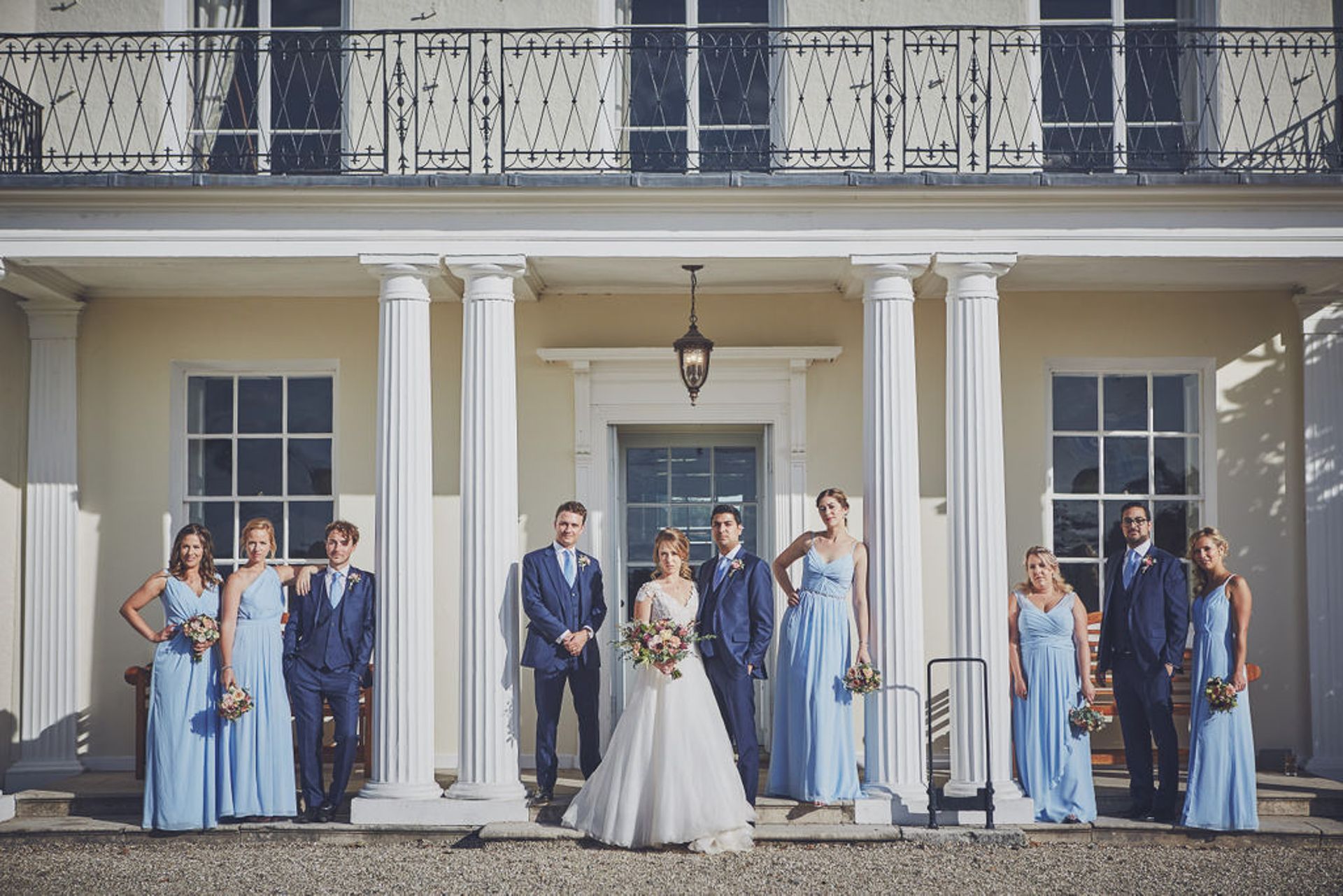 a bride and her wedding party are posing for a picture in front of a large building .