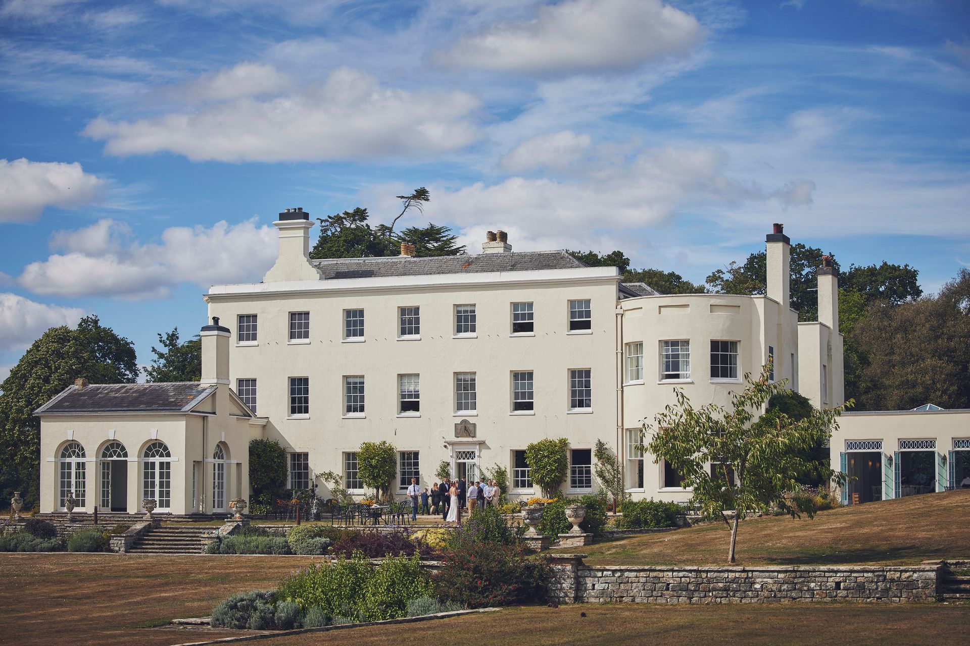 a large white house is sitting on top of a hill in the middle of a field. Wedding venue in Exeter, Devon.
