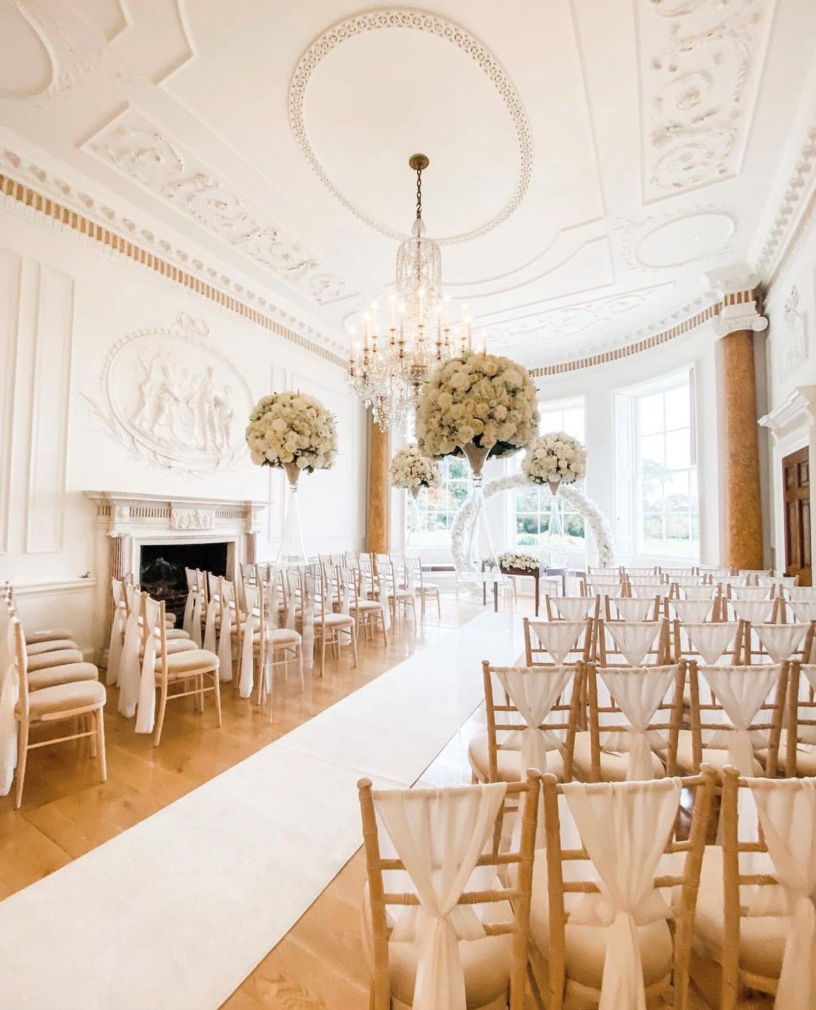 a large room filled with chairs and flowers for a wedding ceremony .
