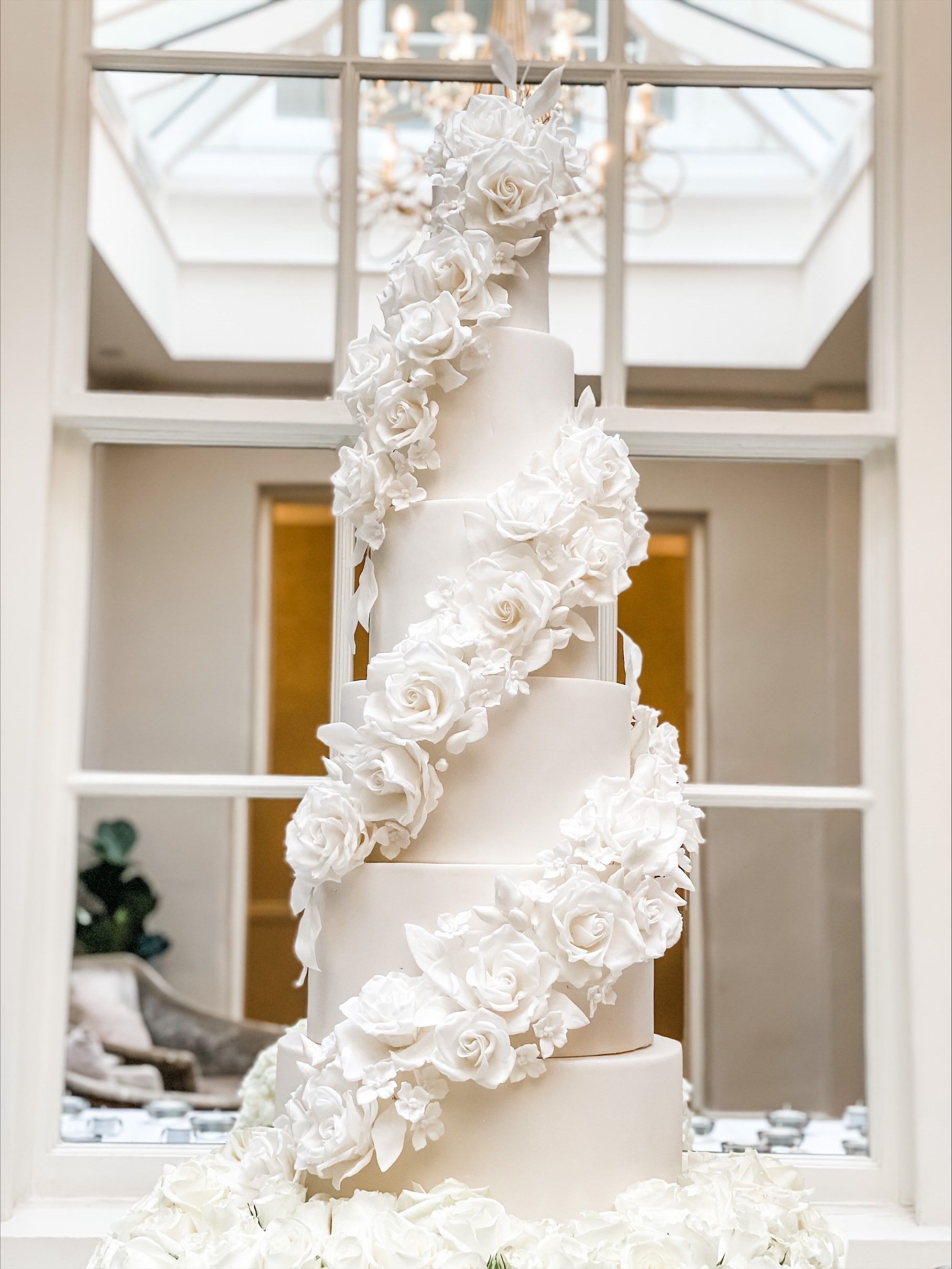 a wedding cake with white flowers on it is sitting on a table in front of a window .