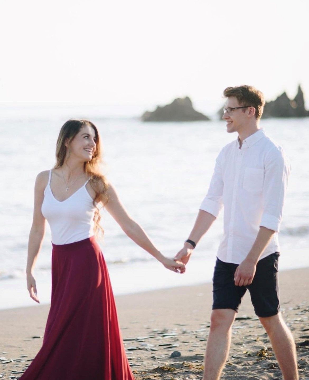 a man and a woman are holding hands on the beach