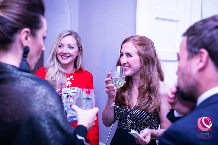 a group of people are standing around a table drinking wine .