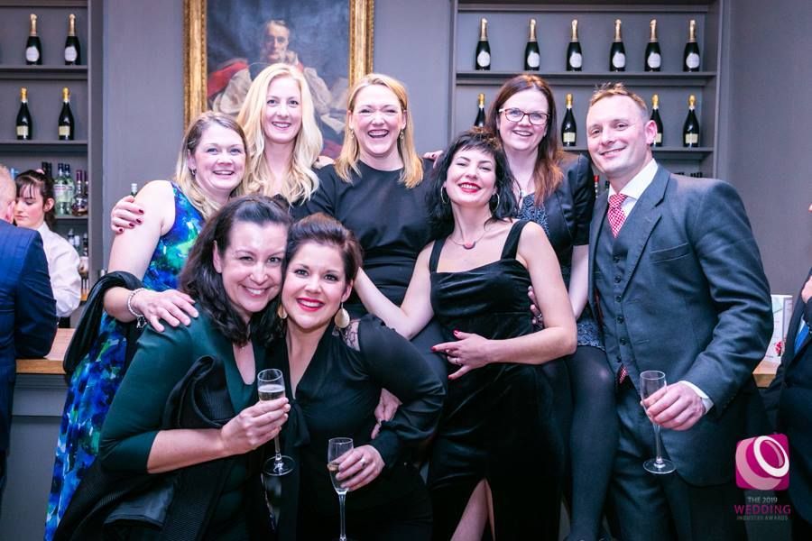 a group of people are posing for a picture while holding champagne glasses .