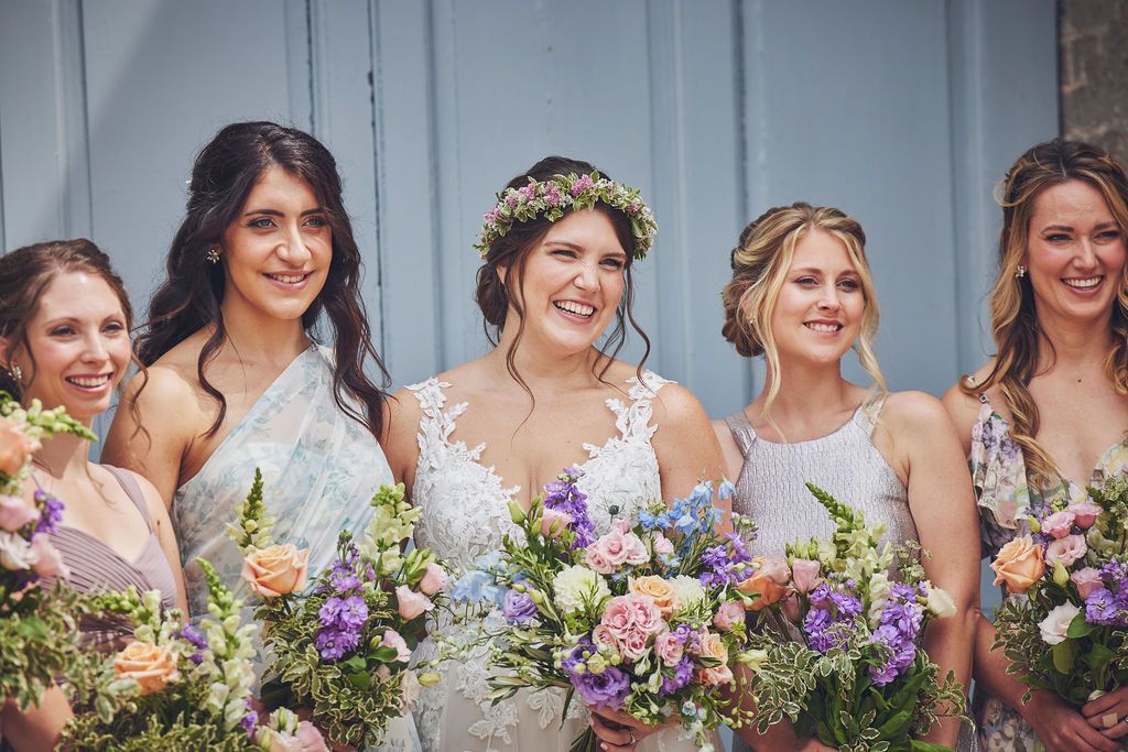 a bride and her bridesmaids are posing for a picture while holding bouquets of flowers .