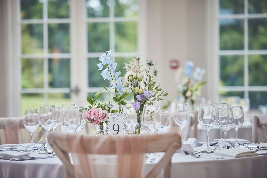 a table set for a wedding reception with a vase of flowers on it.