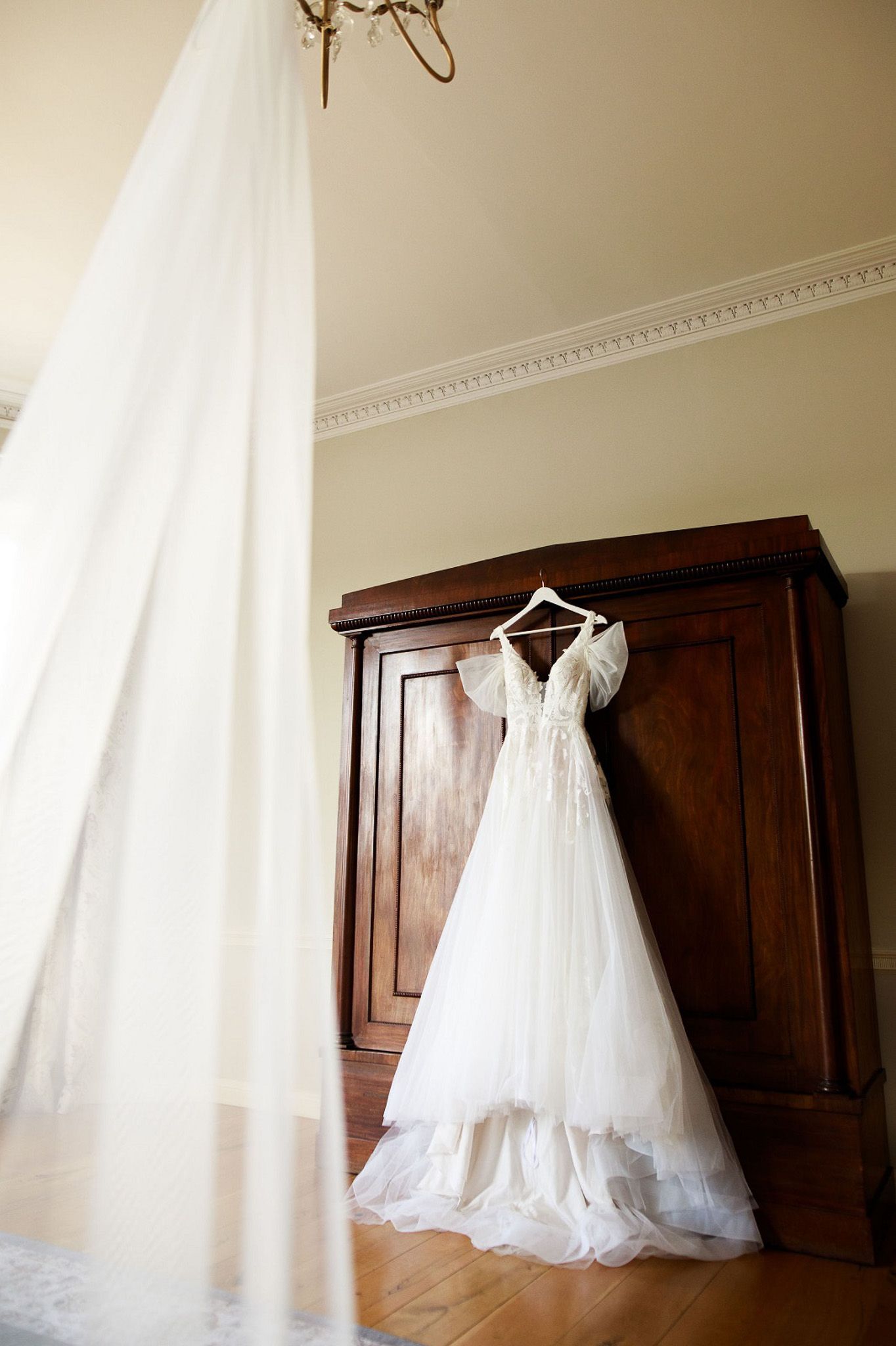 a wedding dress is hanging on a hanger in a room .