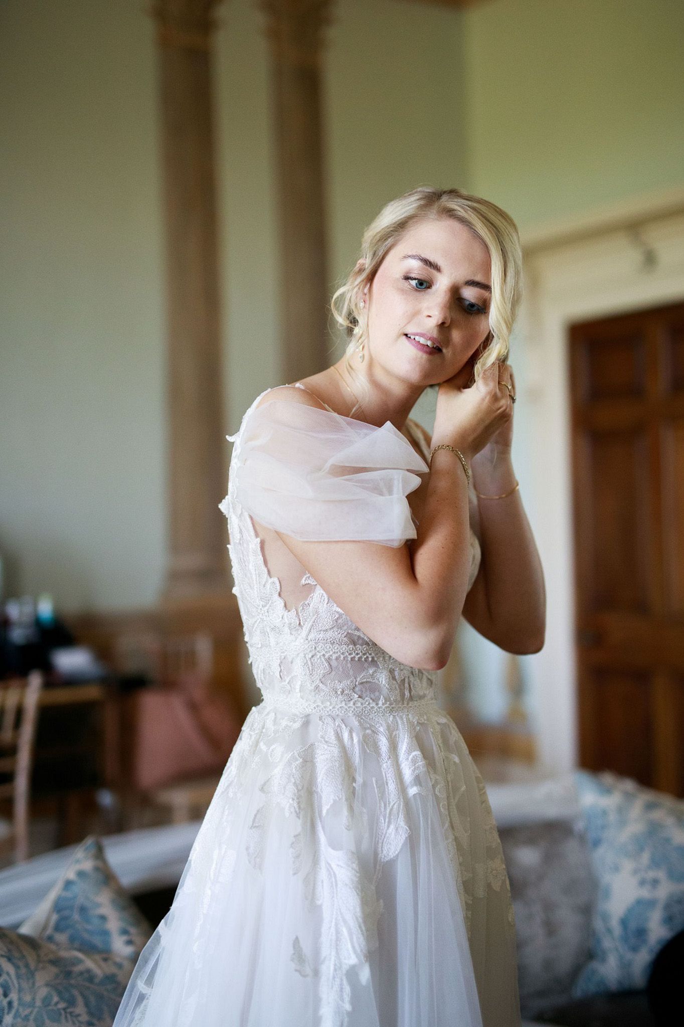 a woman in a wedding dress is putting on her earrings .