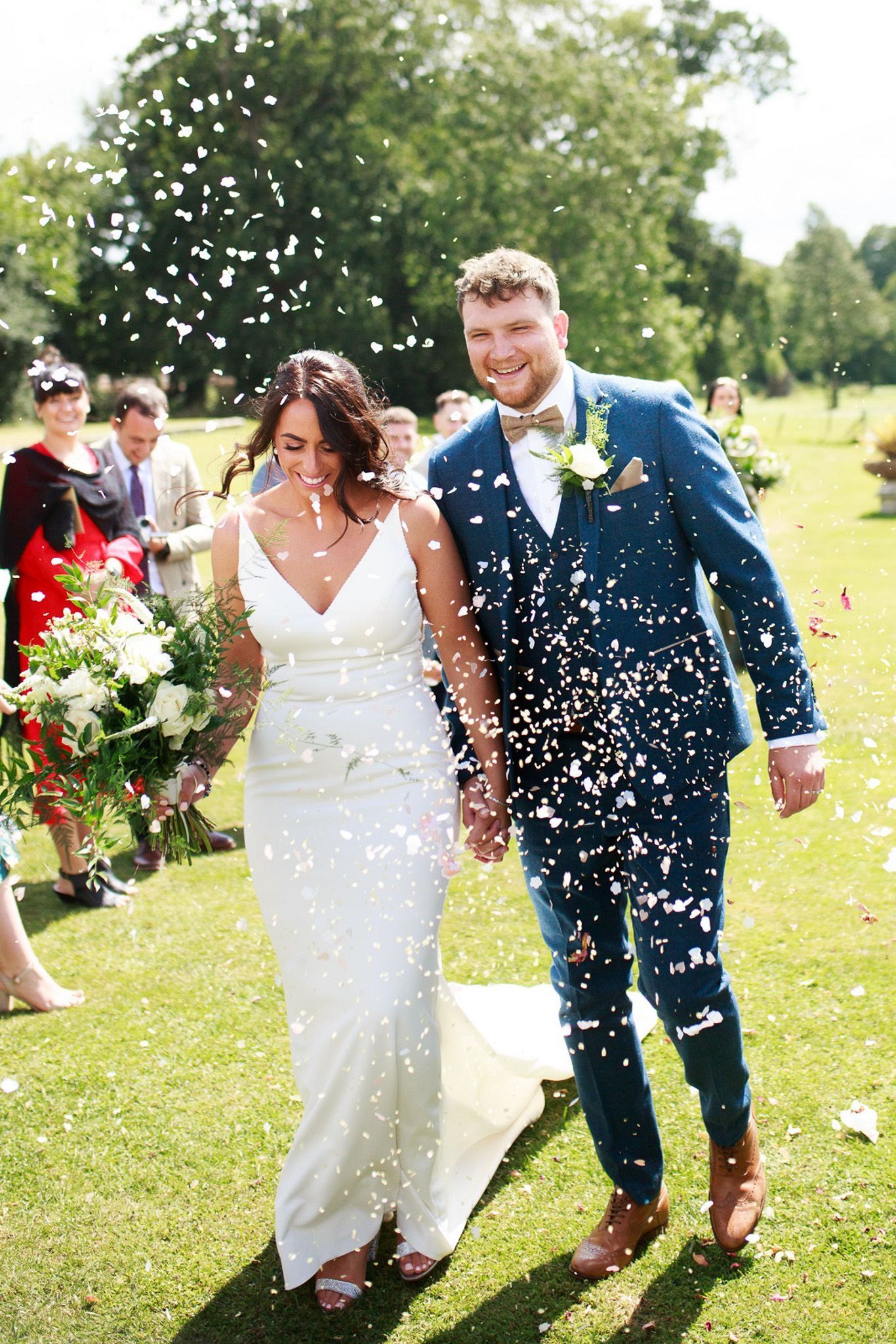 a bride and groom are walking through a field of confetti
