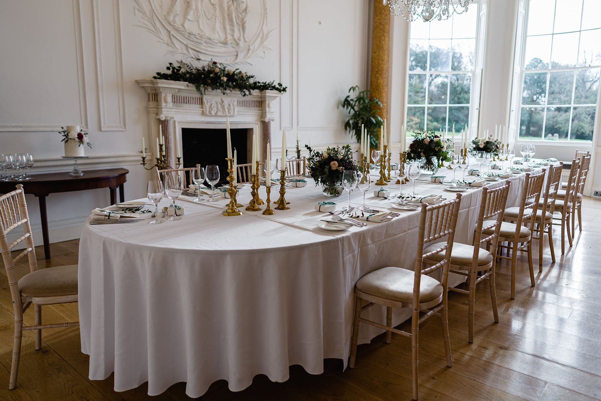 a long table with a white tablecloth and chairs in a room .