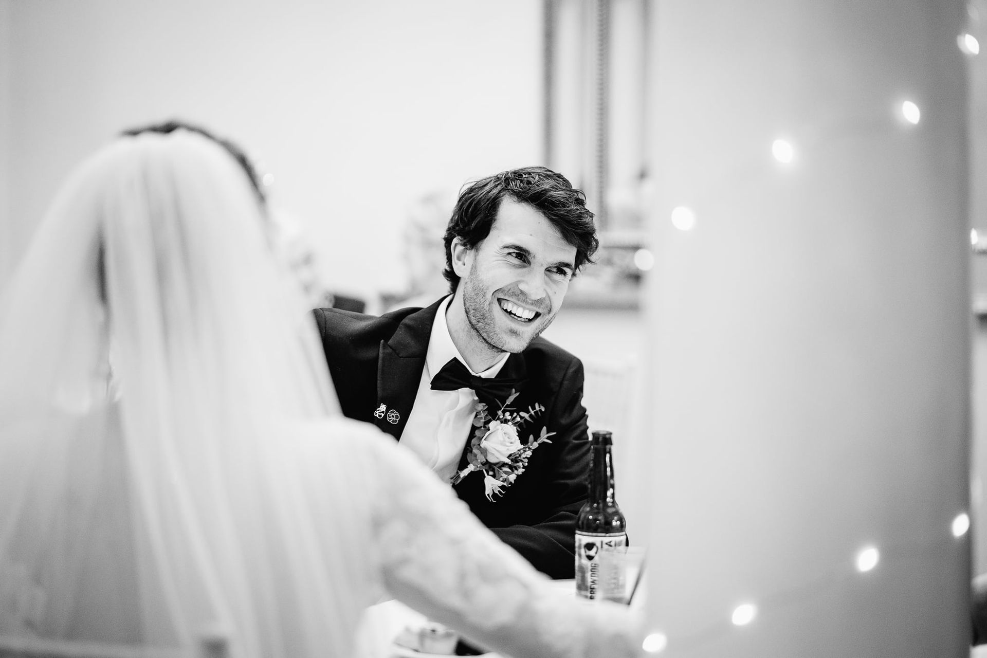 a black and white photo of a bride and groom sitting at a table .
