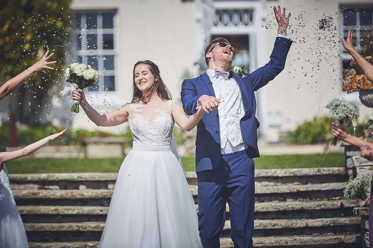 a bride and groom are throwing confetti in the air .