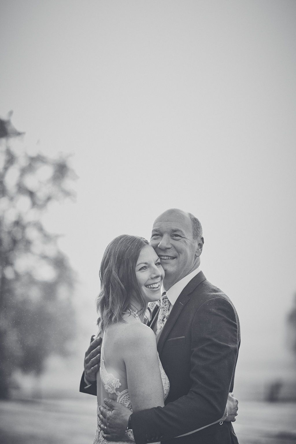 a black and white photo of a bride and groom hugging each other .