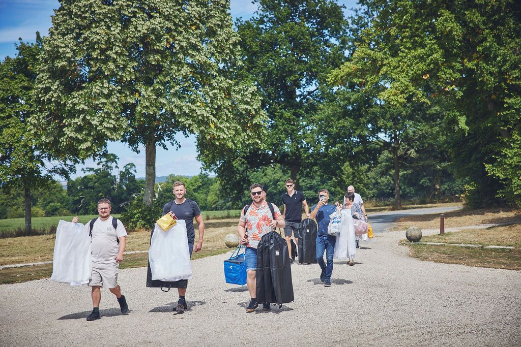 a group of people are walking down a gravel road carrying luggage .