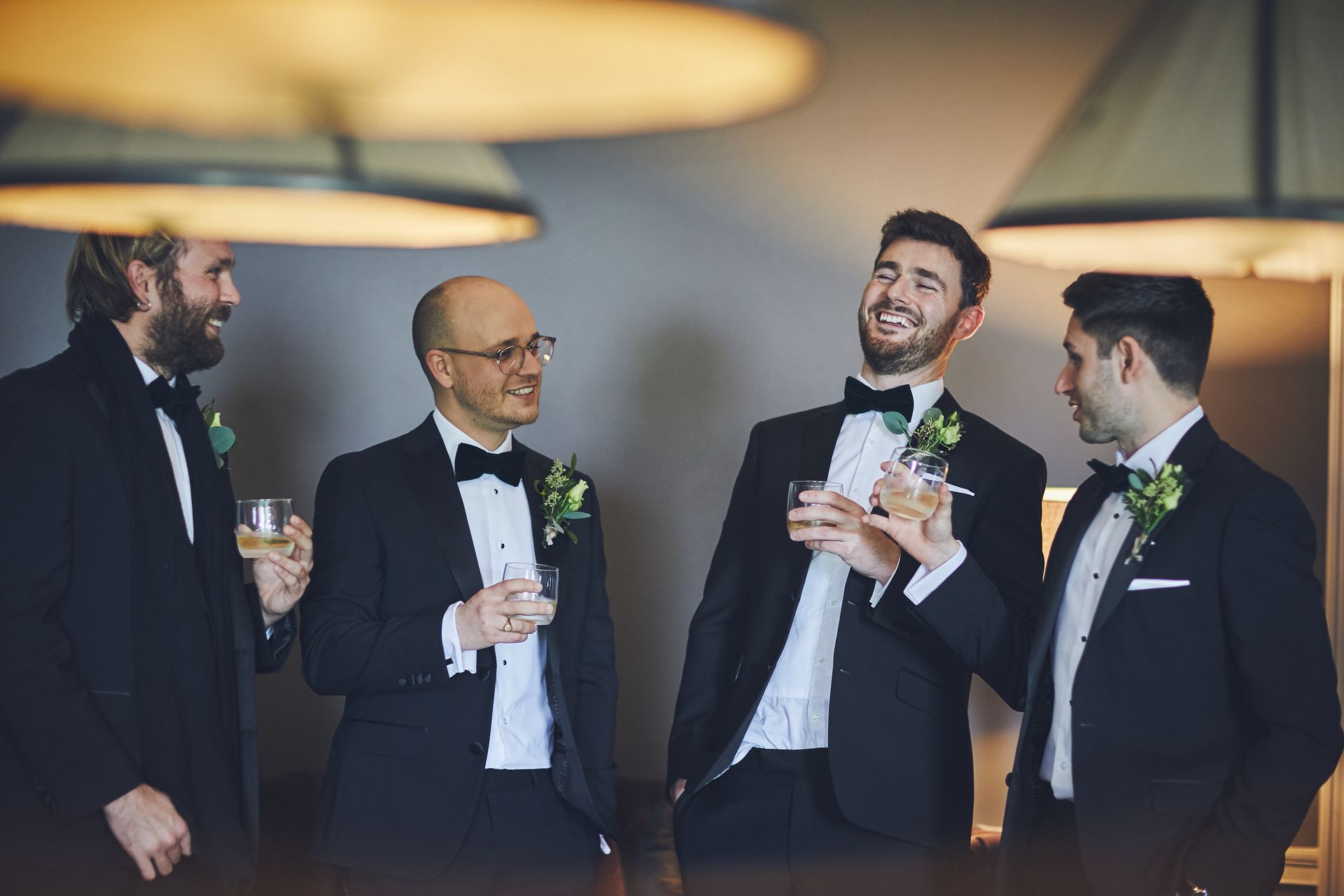 a group of men in tuxedos are standing next to each other holding glasses of wine .