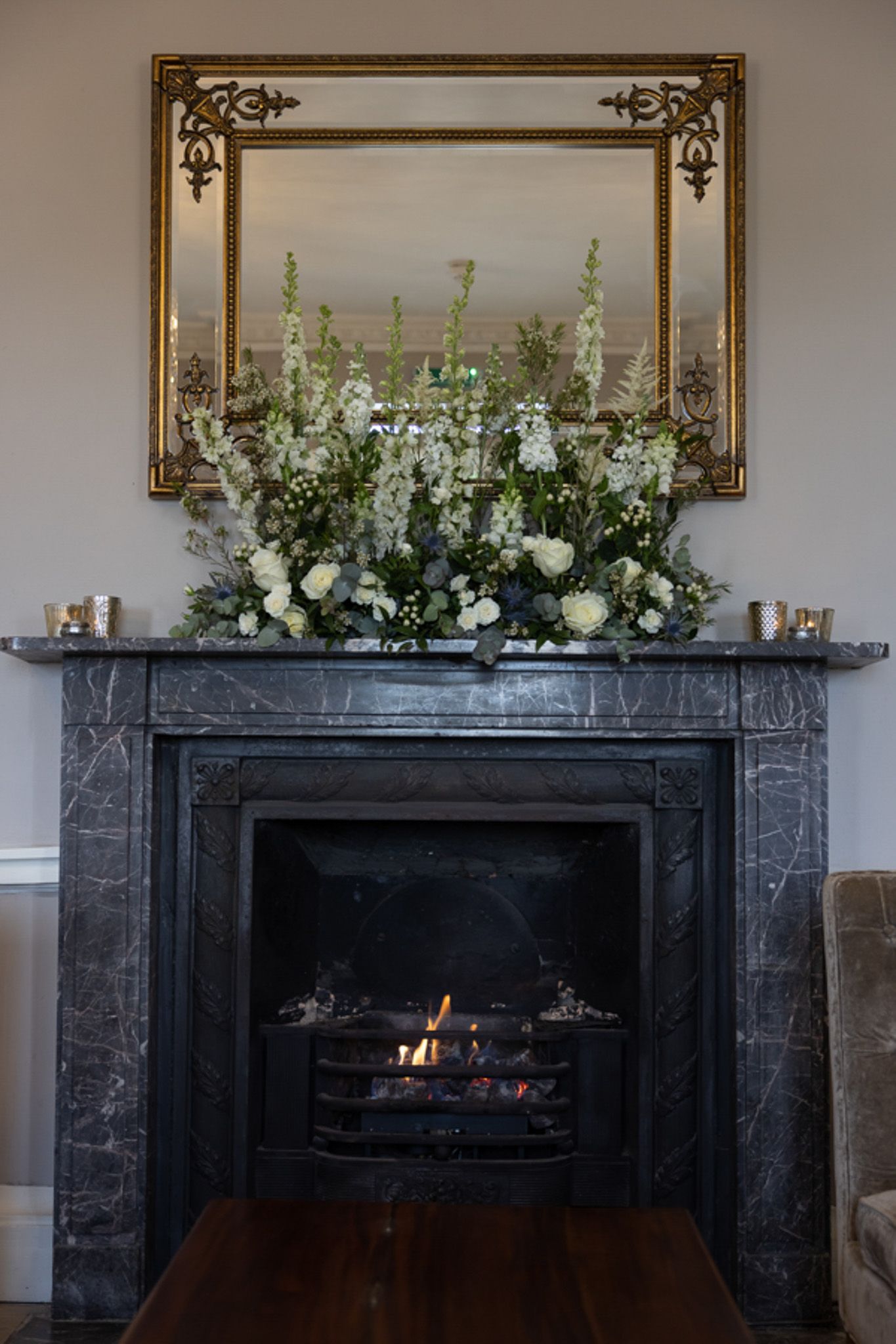 a fireplace with flowers on it and a mirror above it