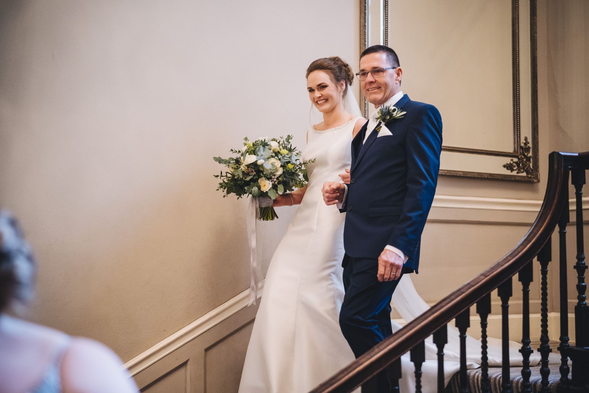 a bride and groom are walking down a set of stairs .