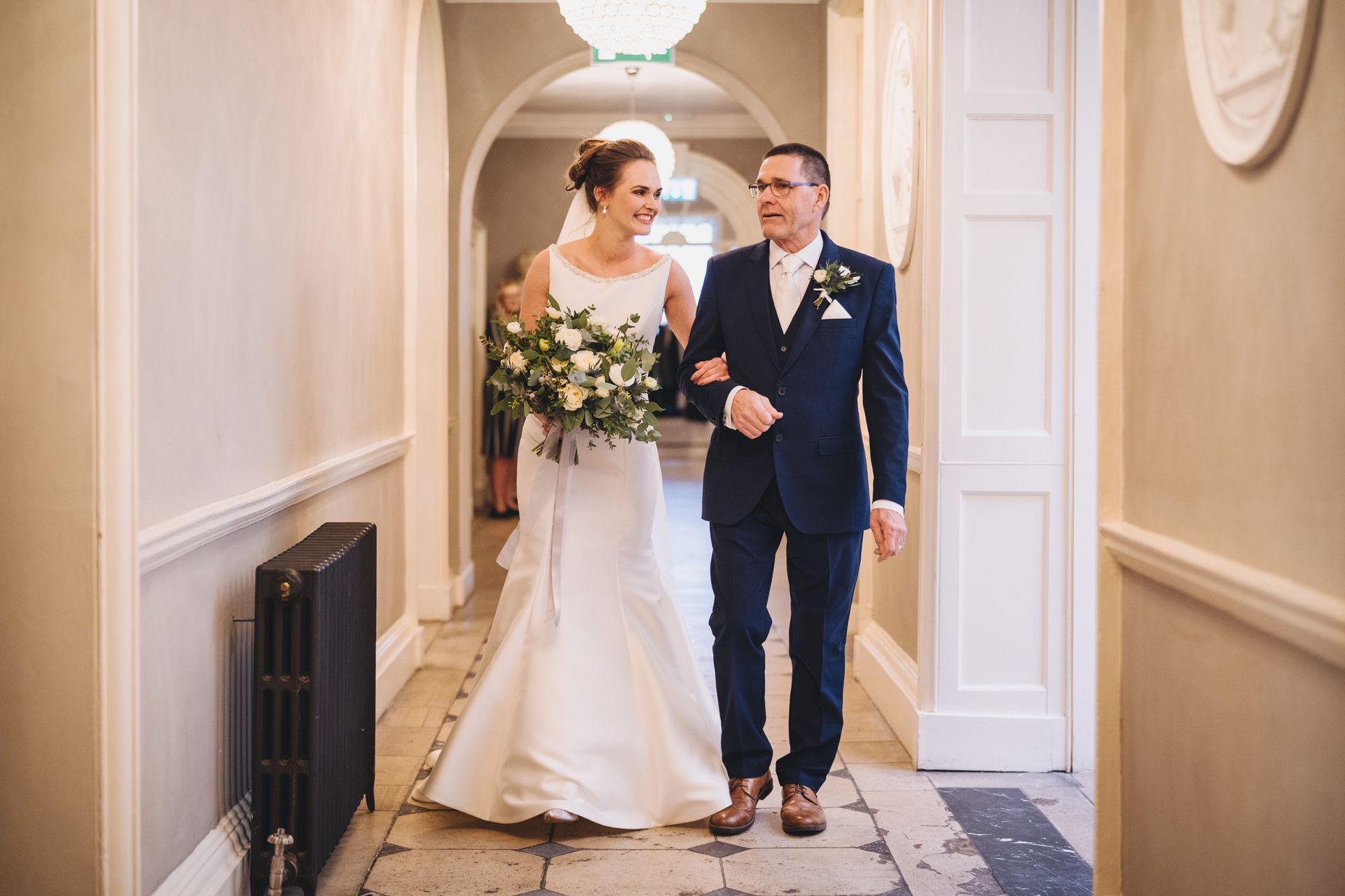 a bride and groom are walking down a hallway .
