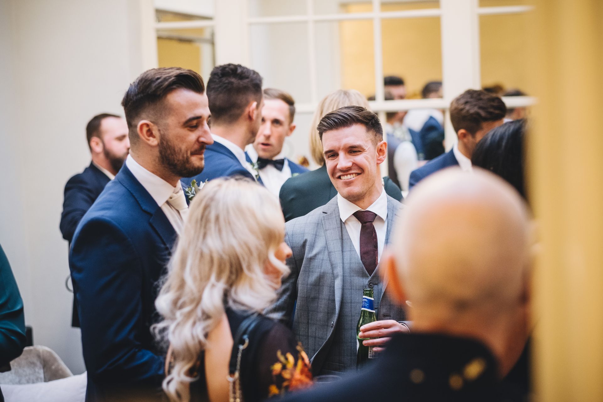 a group of people are standing in a room talking to each other .