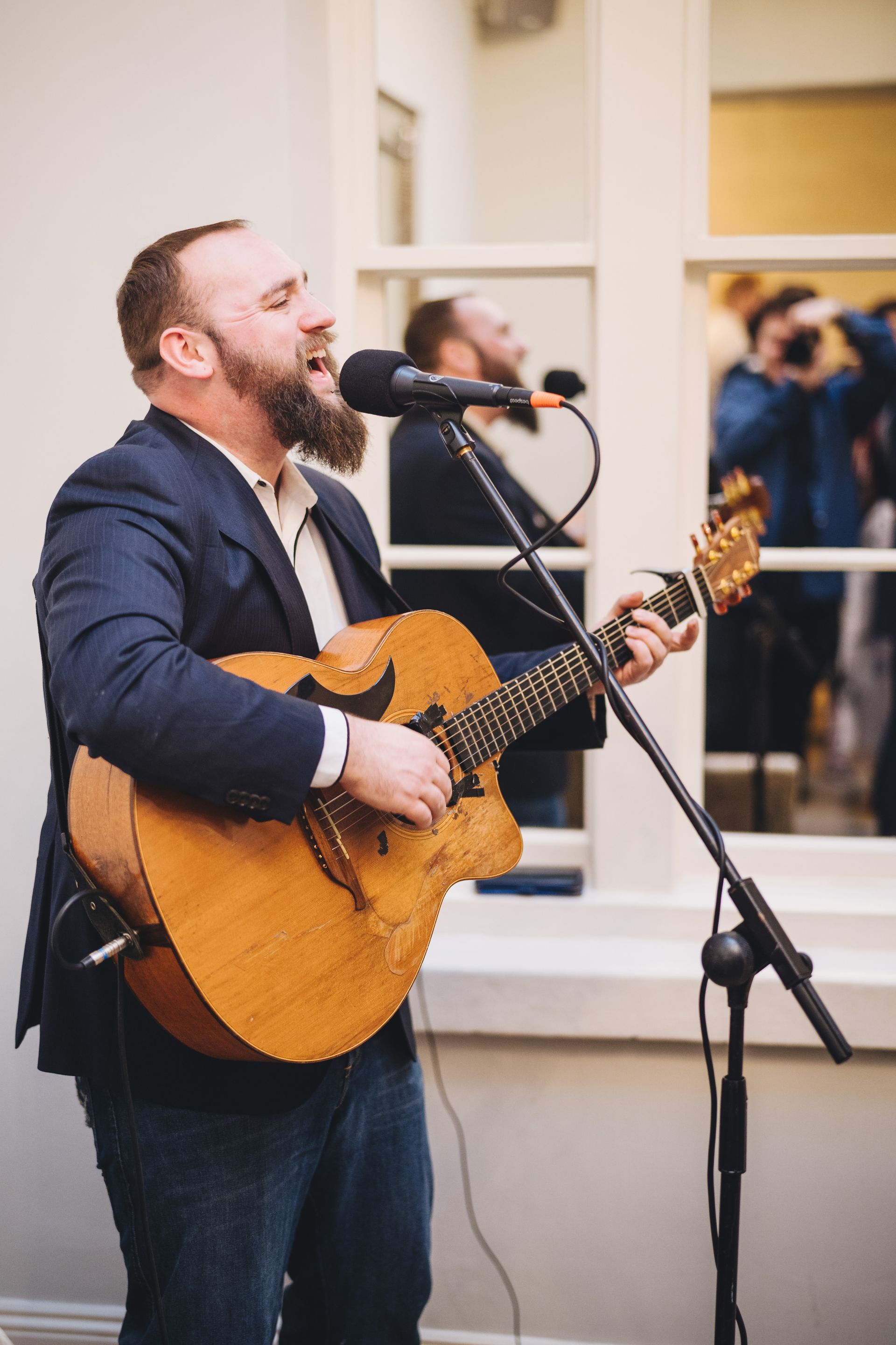 a man in a suit is playing a guitar and singing into a microphone .
