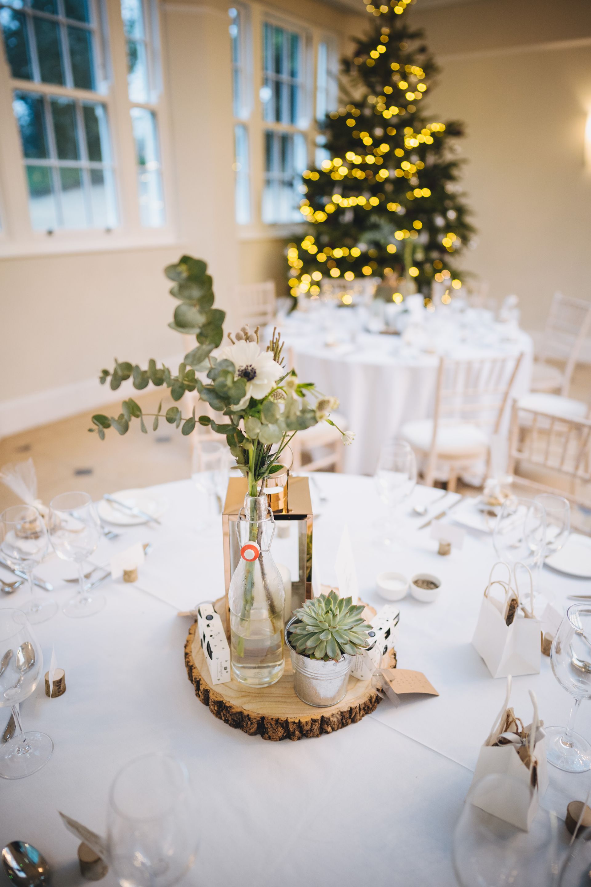 a table set for a wedding reception with a christmas tree in the background .