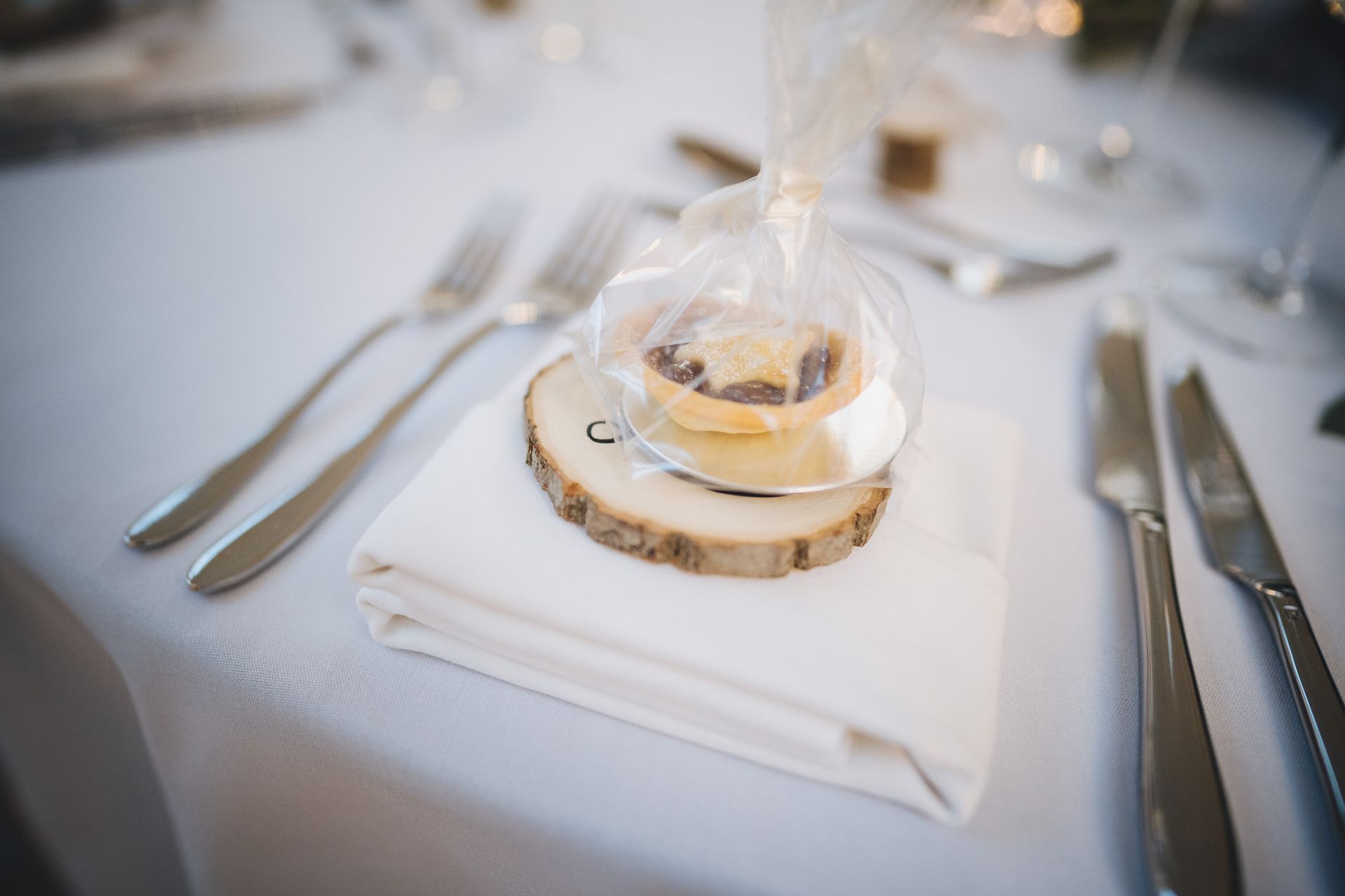 a wooden slice on a napkin on a table with silverware.